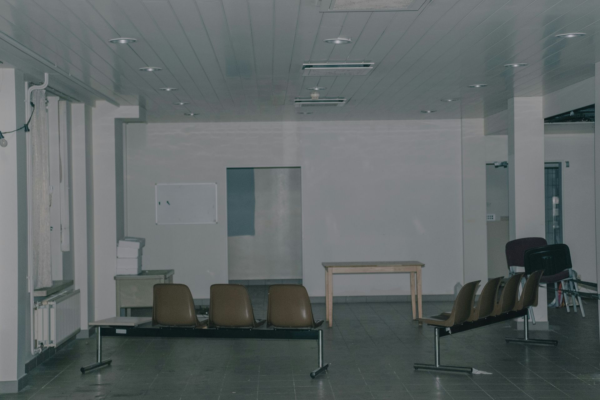 Empty waiting room with chairs, white walls, and a table.