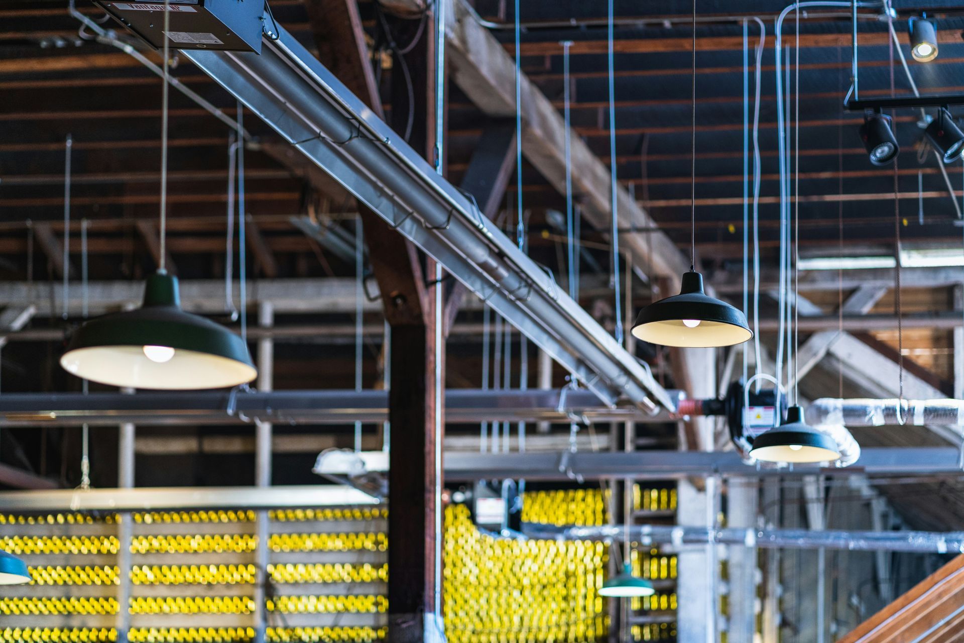 Industrial interior with hanging green lamps and exposed beams.