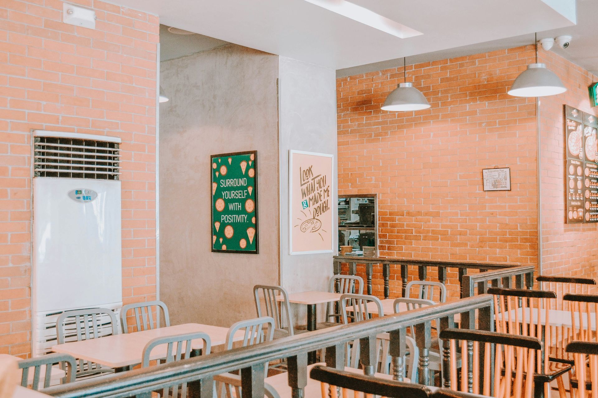 Restaurant interior with brick walls, tables, chairs, and wall art.