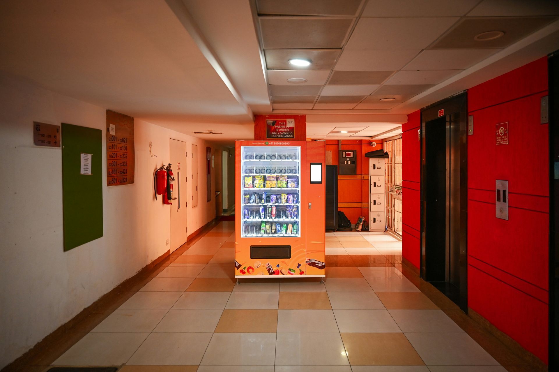 Hallway with a vending machine, an elevator, and an open door.