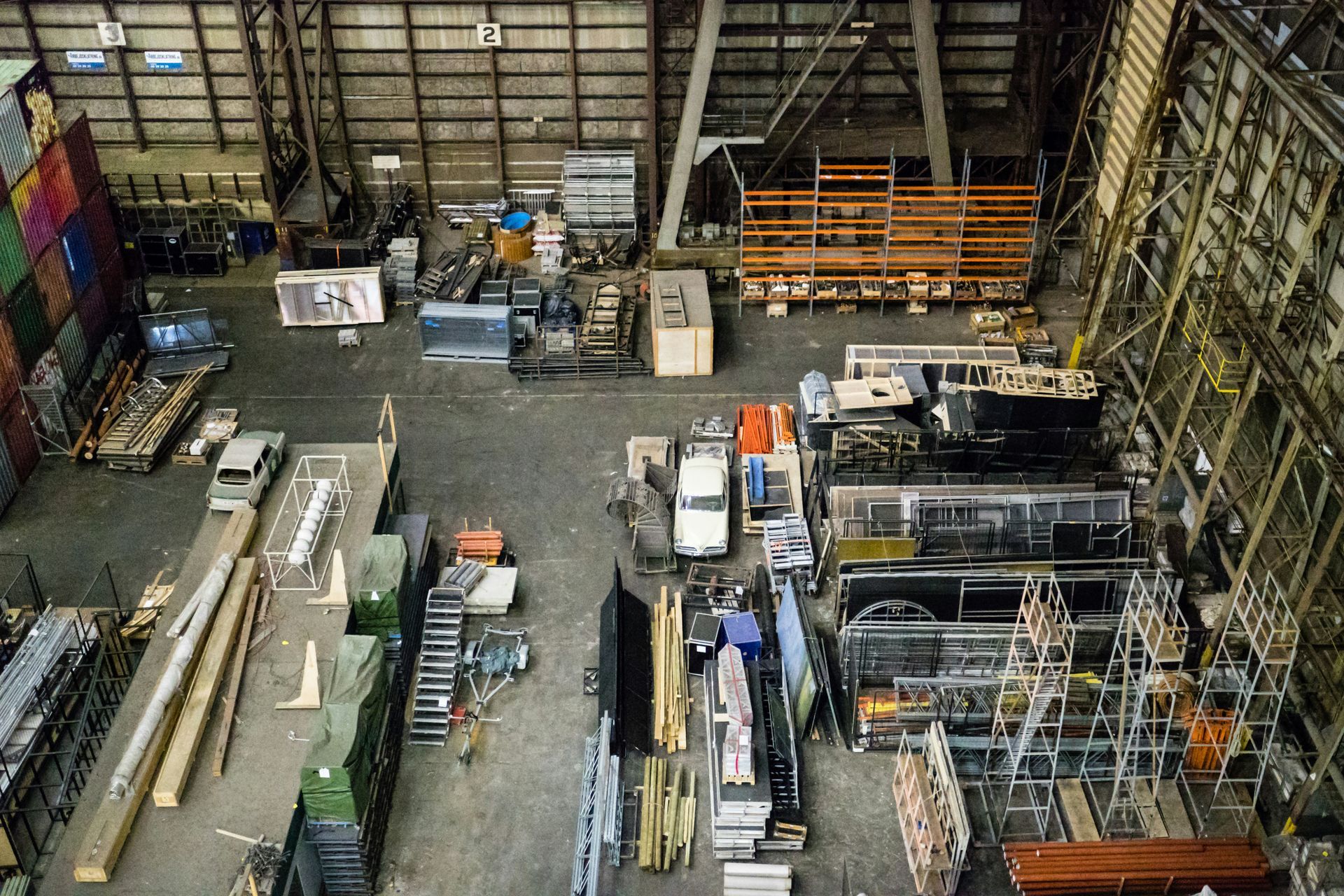Overhead view of a cluttered warehouse with various equipment, containers, and materials.
