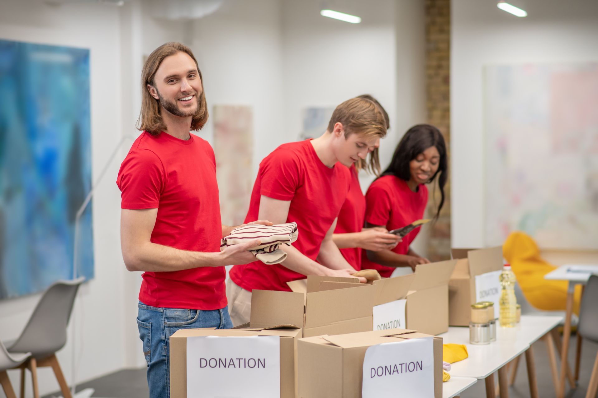 Volunteers in red shirts sort donations into boxes labeled