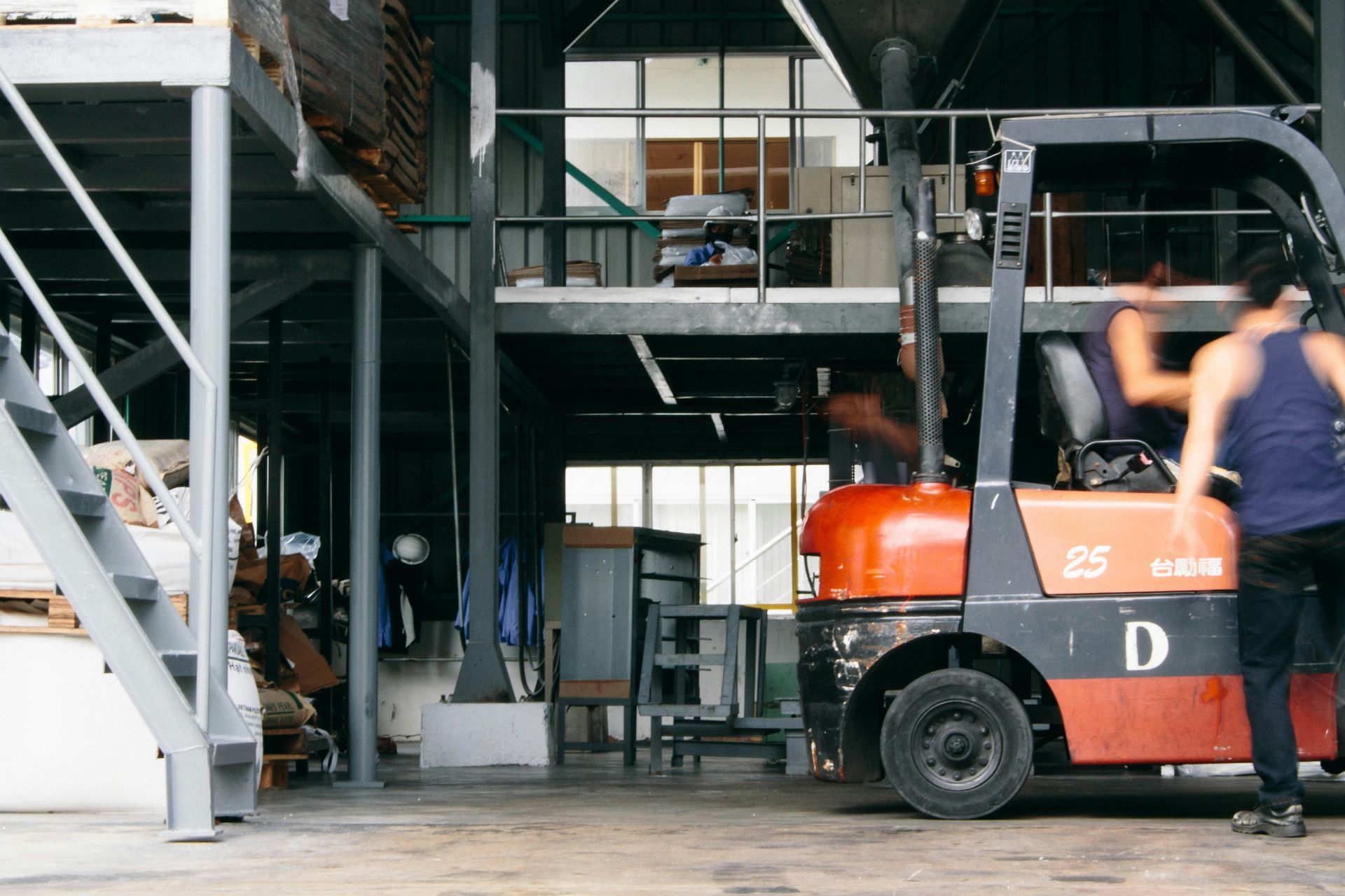 Forklift in a warehouse with a person blurred in motion.