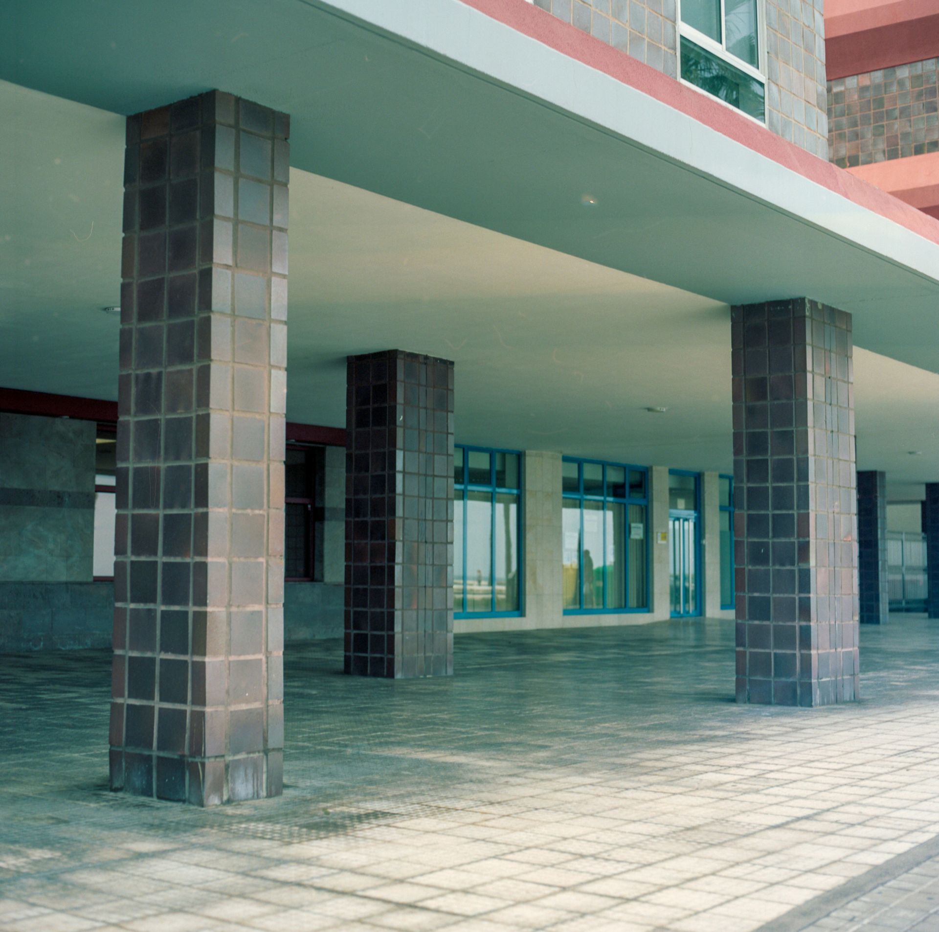 Covered walkway with tiled pillars, windows, and red trim.