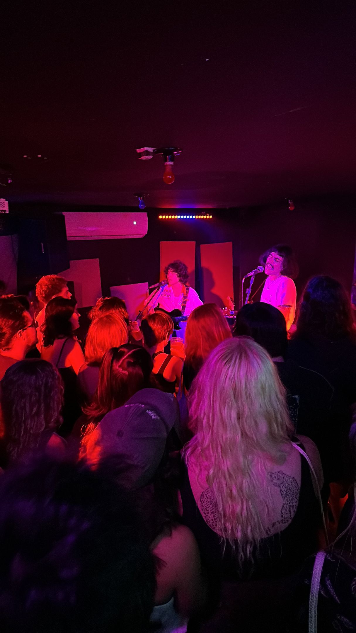 Uma multidão de pessoas está sentada em uma sala escura em um show.