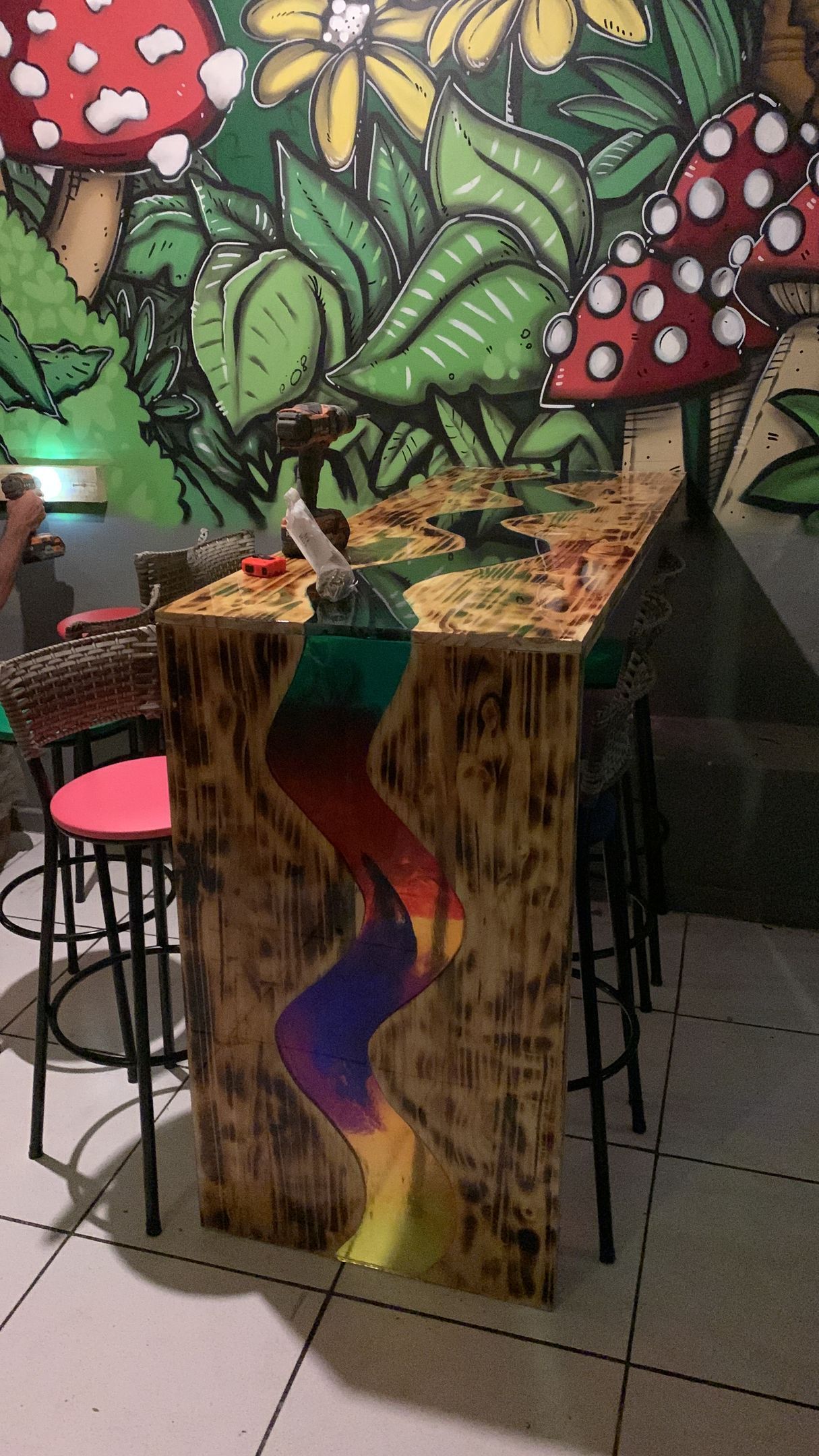 Uma mesa de madeira com uma pintura de cogumelos na parede atrás dela.