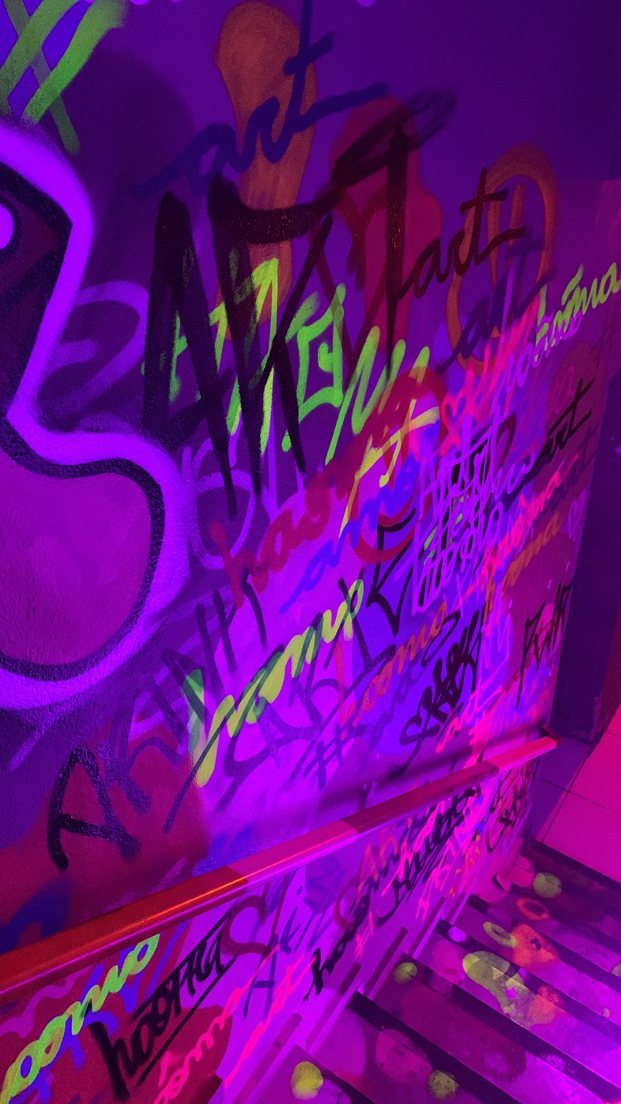 Um close de uma parede roxa com grafite neon.