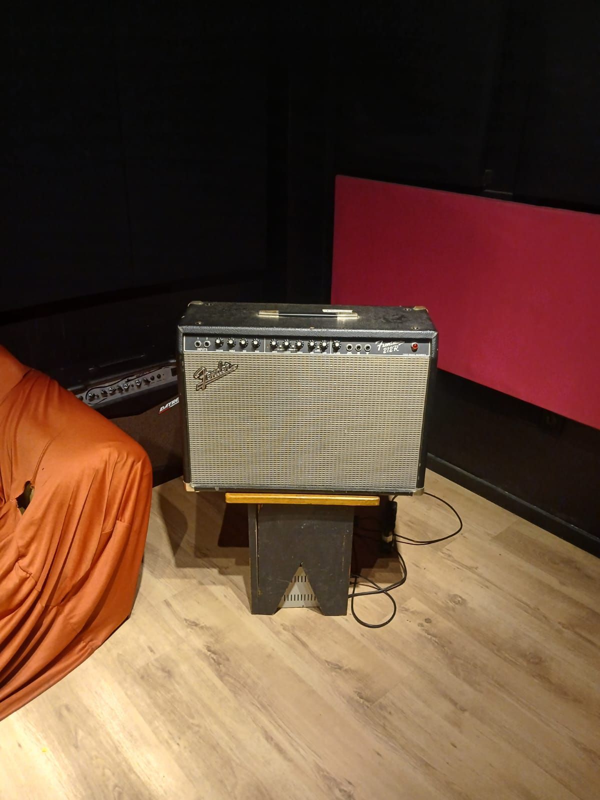 Um amplificador Fender está sobre um banquinho em uma sala escura