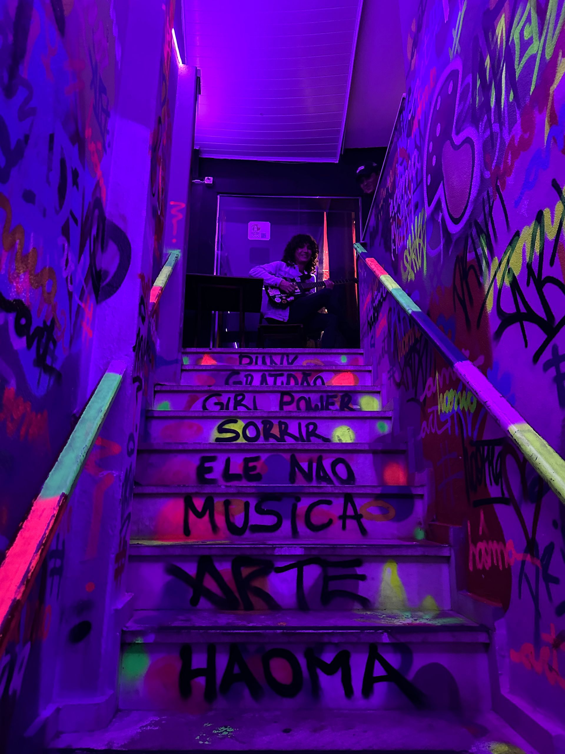 Uma pessoa está parada em um lance de escadas coberto de pichações.