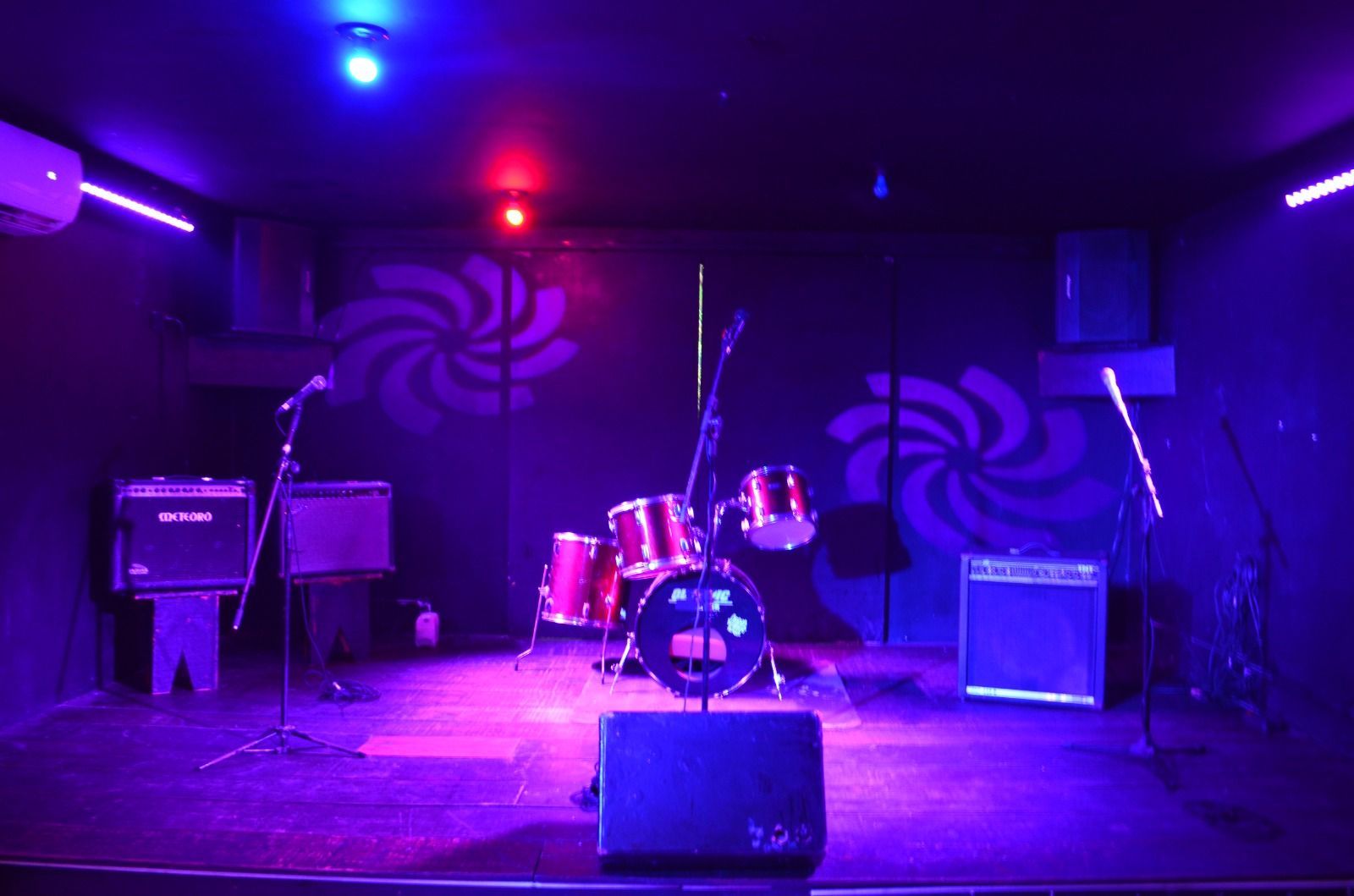 Um palco vazio com luzes roxas e uma bateria