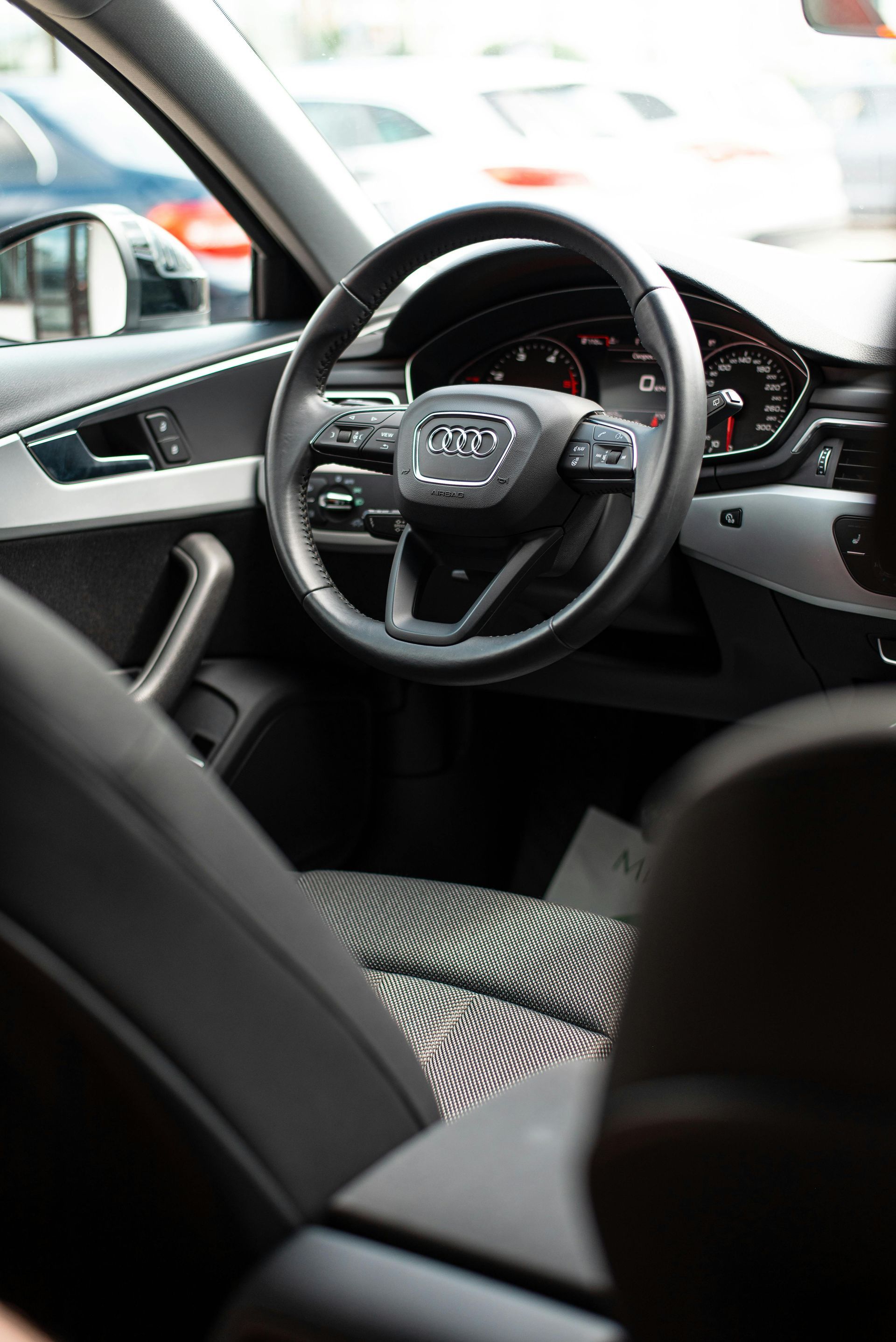 Interior view of an Audi car with a black steering wheel, dashboard, and seat.