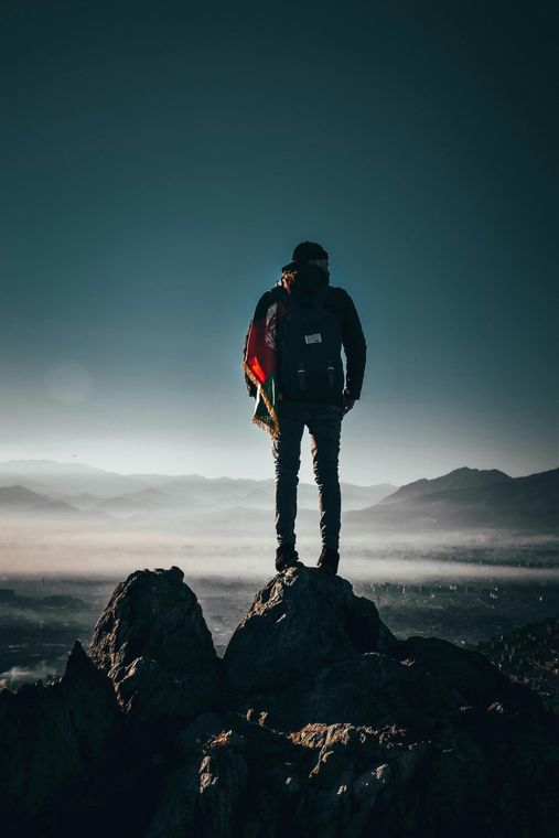 A man with a backpack is standing on top of a mountain.
