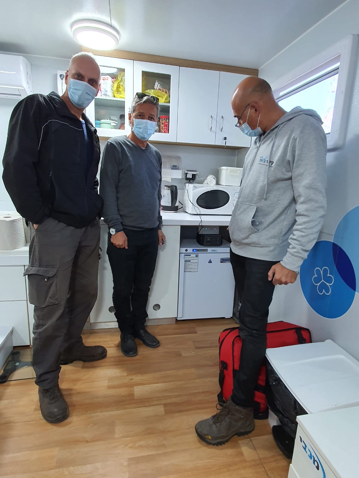 שלושה גברים עוטים מסכות פנים עומדים במטבח