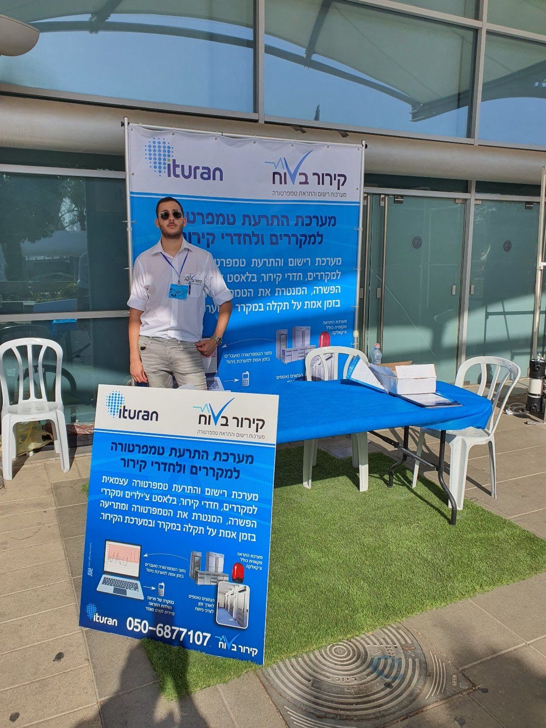 גבר עומד מול שולחן ועליו שלט.