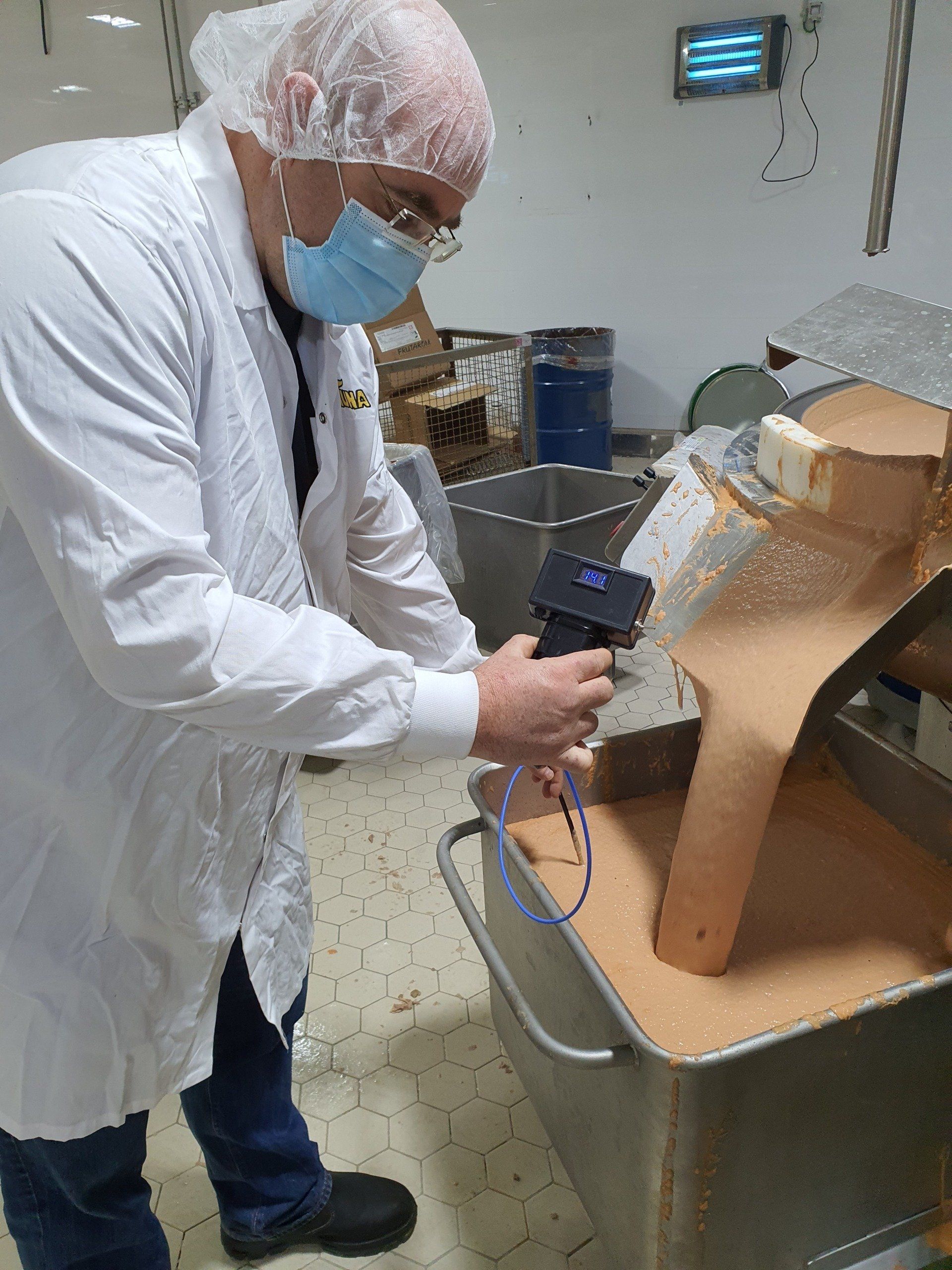 גבר בחלוק מעבדה ומסכה עובד על מכונה.