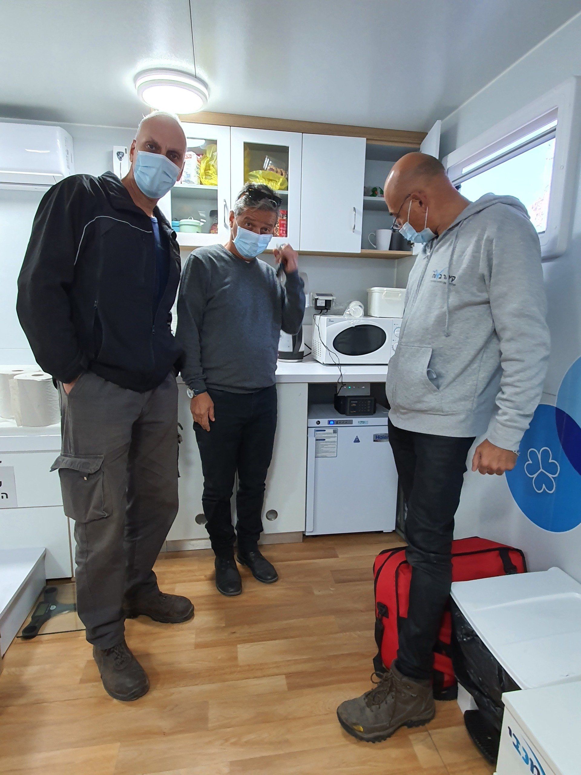 שלושה גברים עוטים מסכות פנים עומדים במטבח