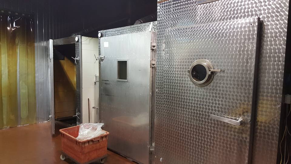 חדר עם הרבה מכשירי נירוסטה וסל על הרצפה.