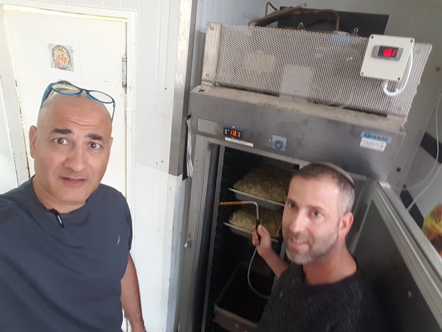 שני גברים עומדים זה ליד זה מול מקרר.