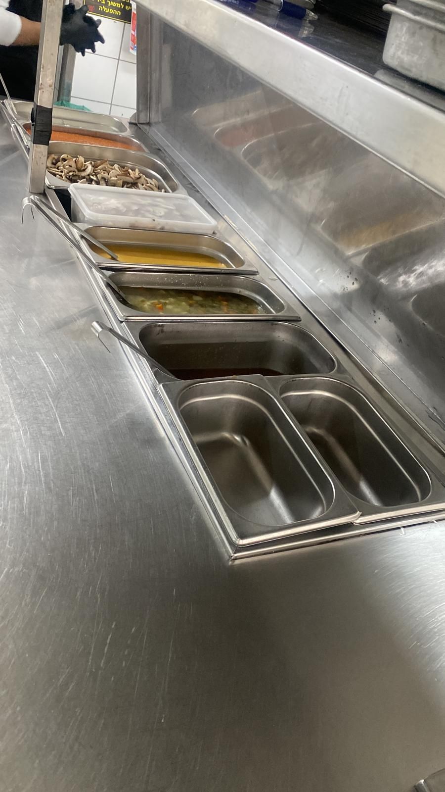 דלפק נירוסטה ועליו מגשי אוכל.