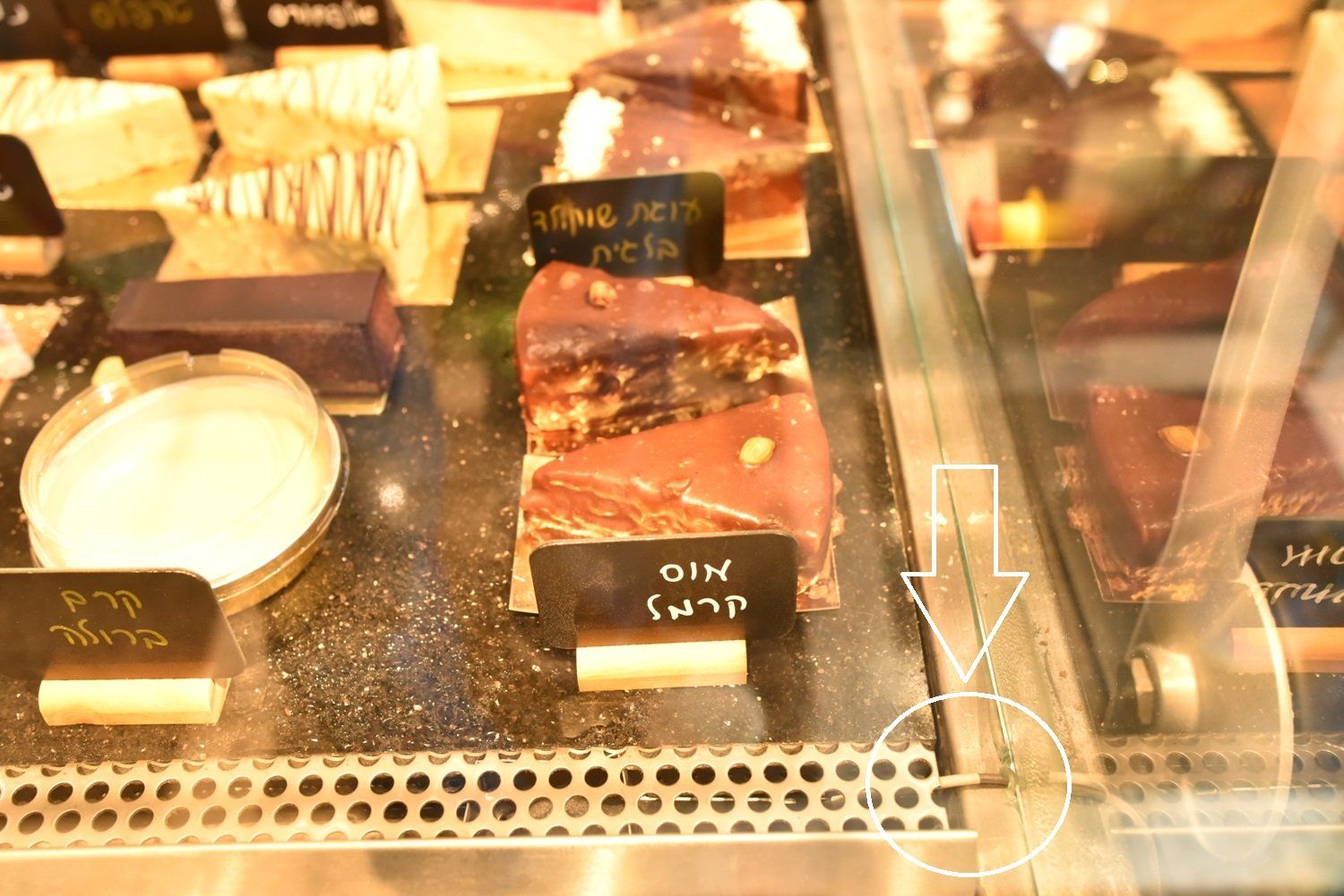 ויטרינה מלאה במגוון קינוחים כולל פרוסת עוגת שוקולד