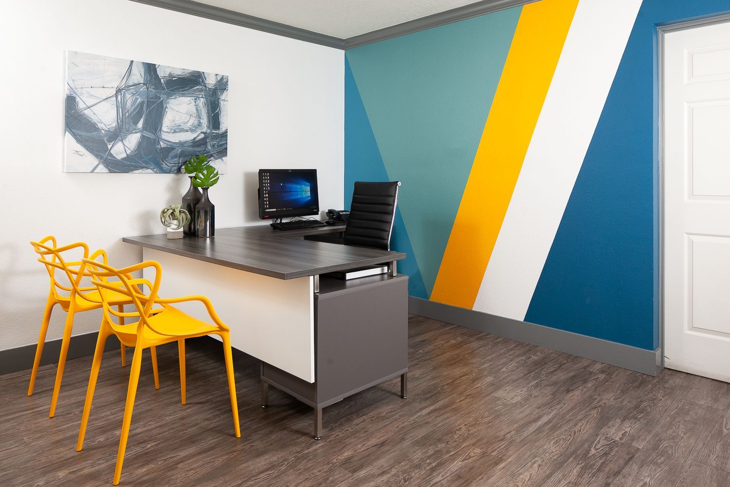 A room with a desk , chairs , and a computer.