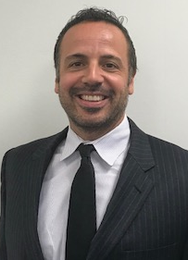 Agent Chris in a suit and tie is smiling for the camera.