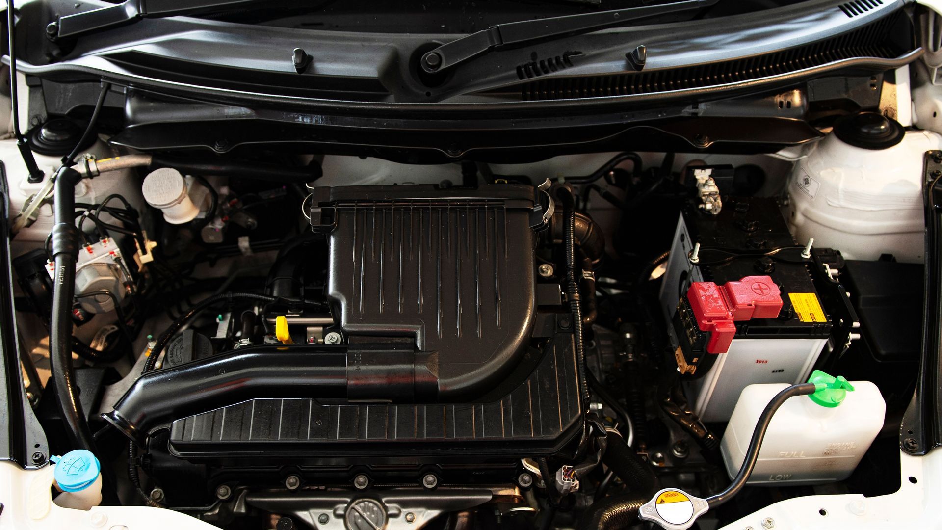 A close up of a car engine with the hood open.