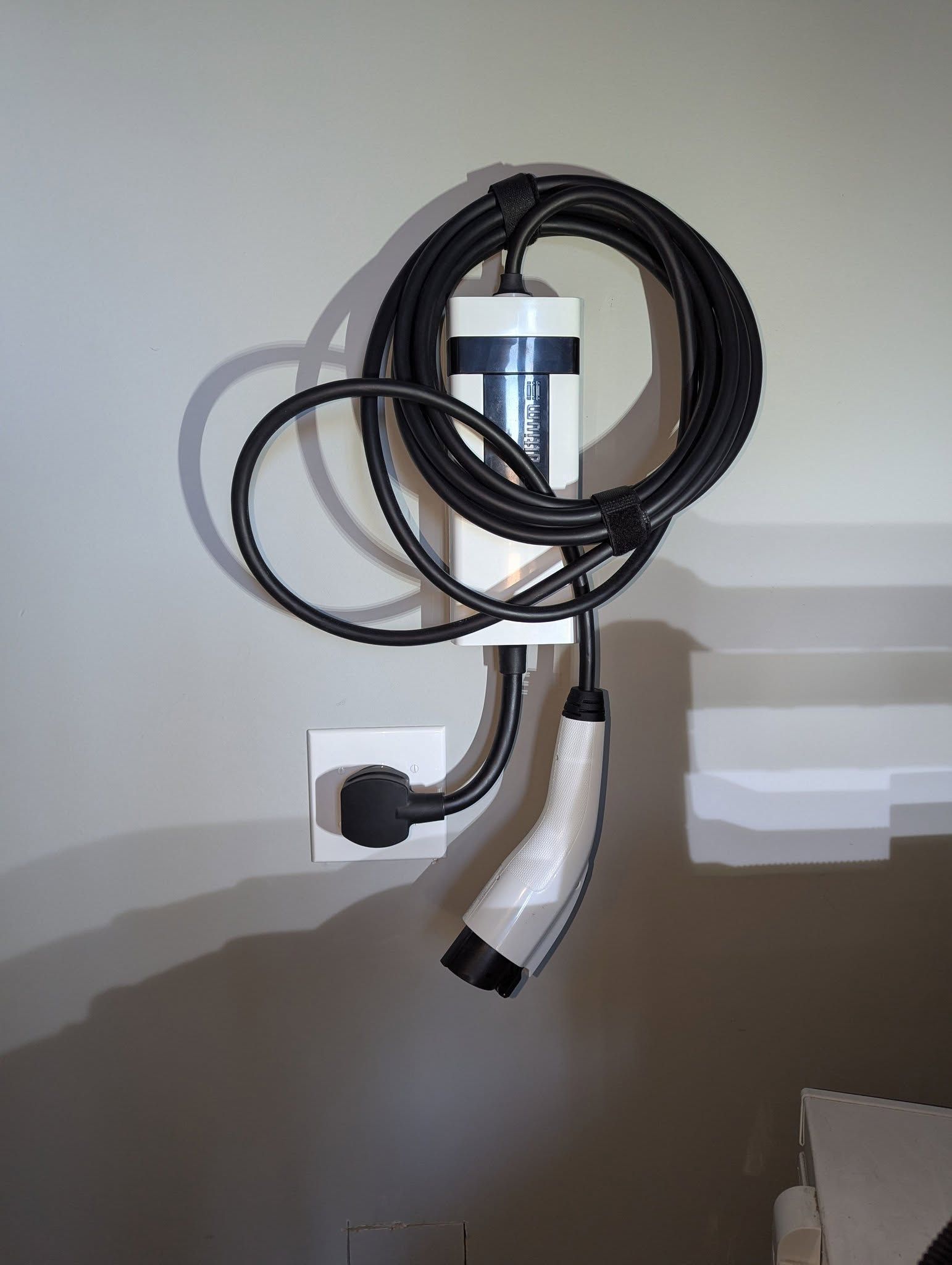 A hose is hanging on a wall next to a plug