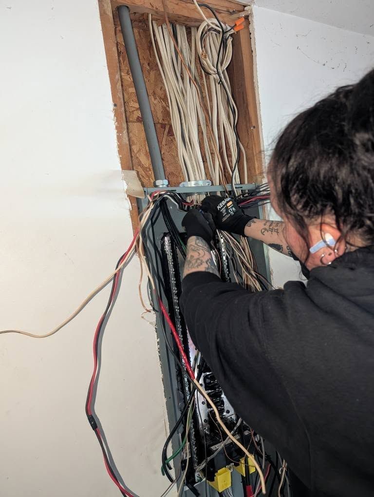 A woman is working on an electrical box in a room.