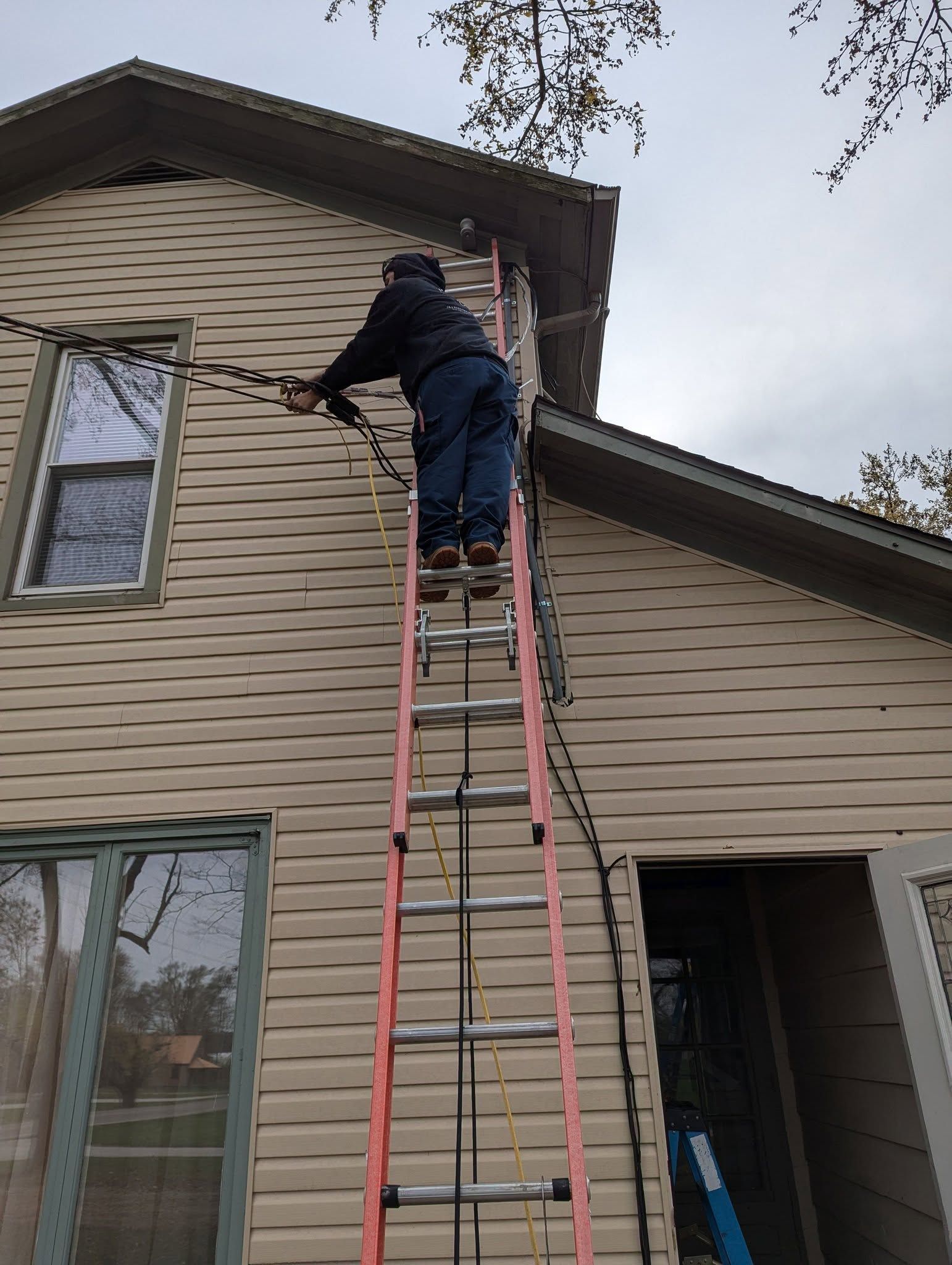A man is standing on a ladder on the side of a house.