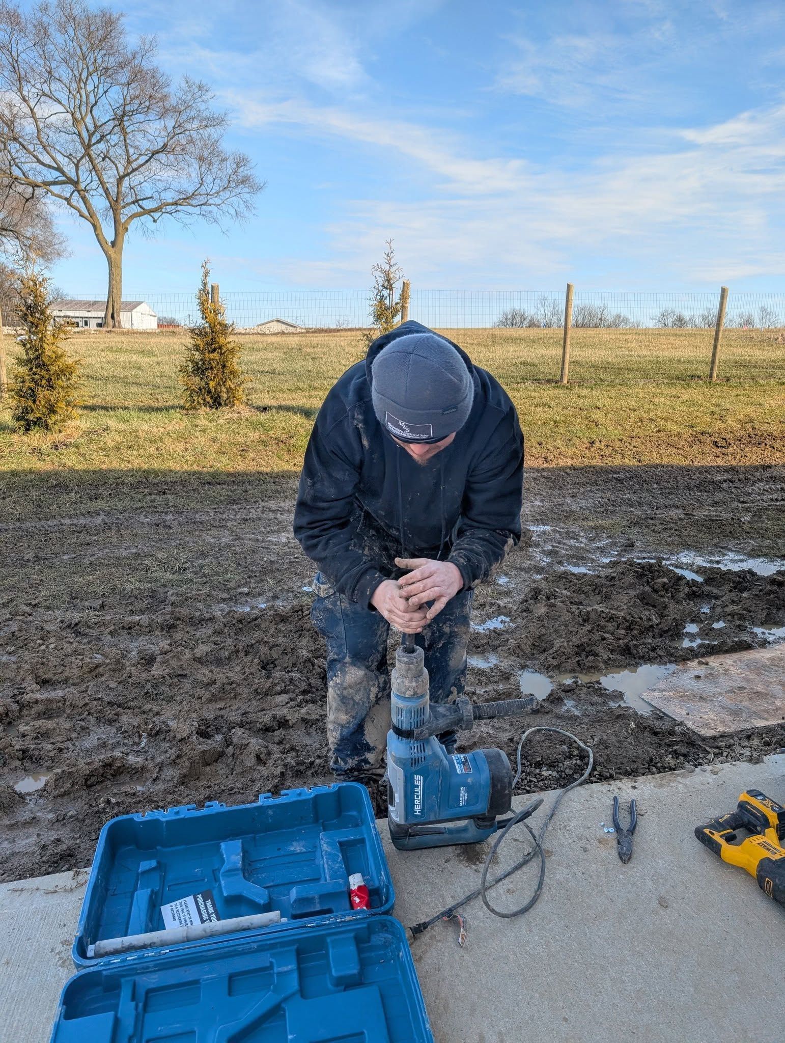 A man is using a hammer to drill a hole in the ground.