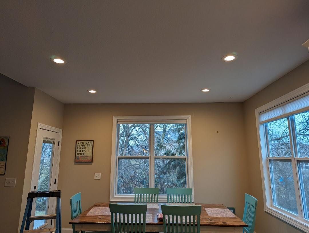 A dining room with a table and chairs and a ladder.
