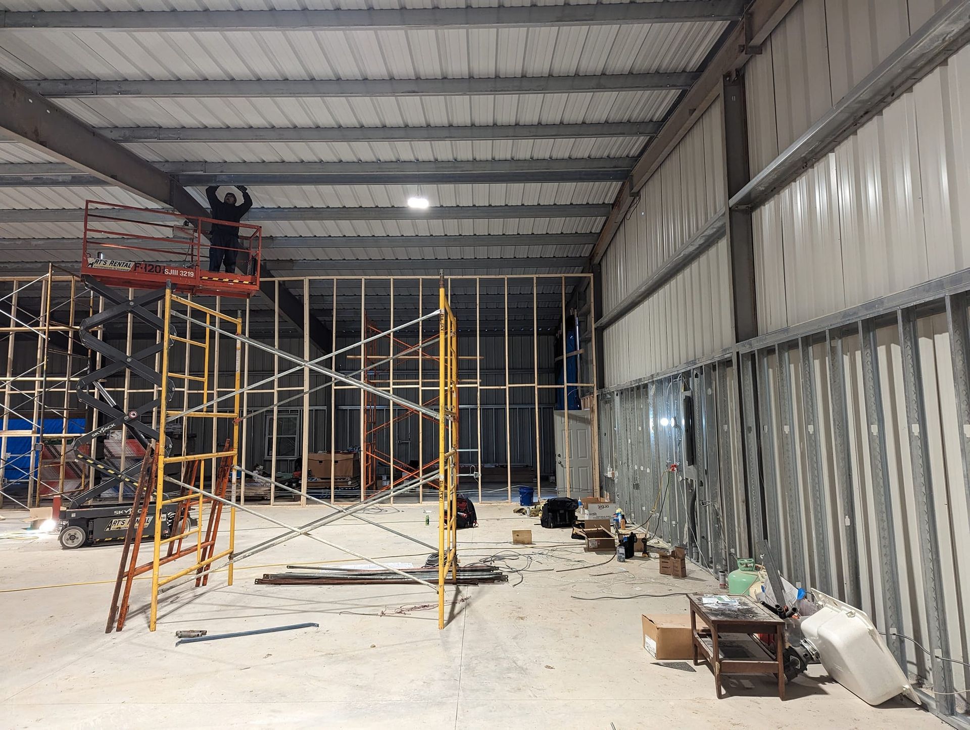 A large building under construction with scaffolding and a man on a ladder.