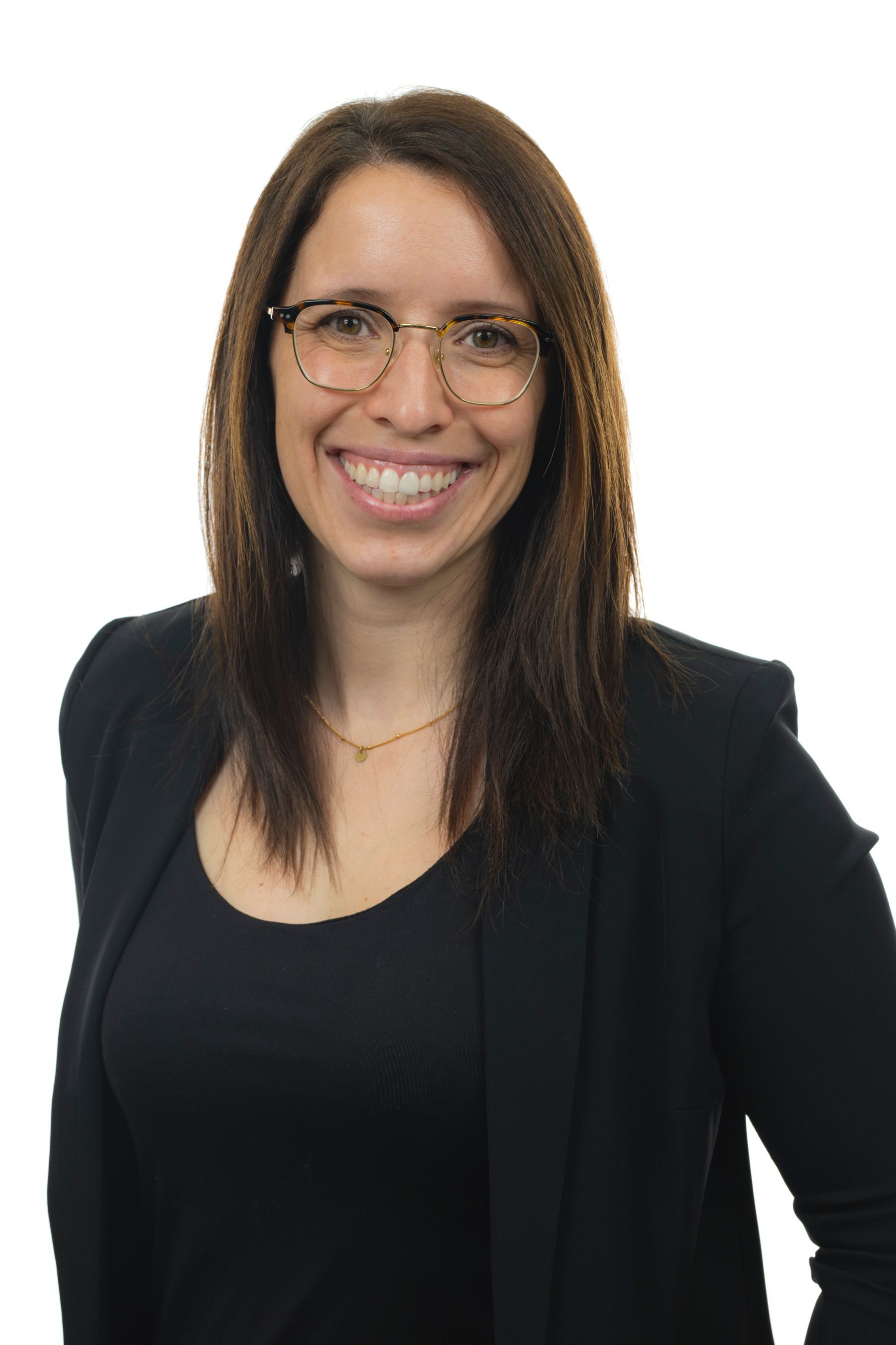 Une femme portant des lunettes et une veste noire sourit à la caméra.