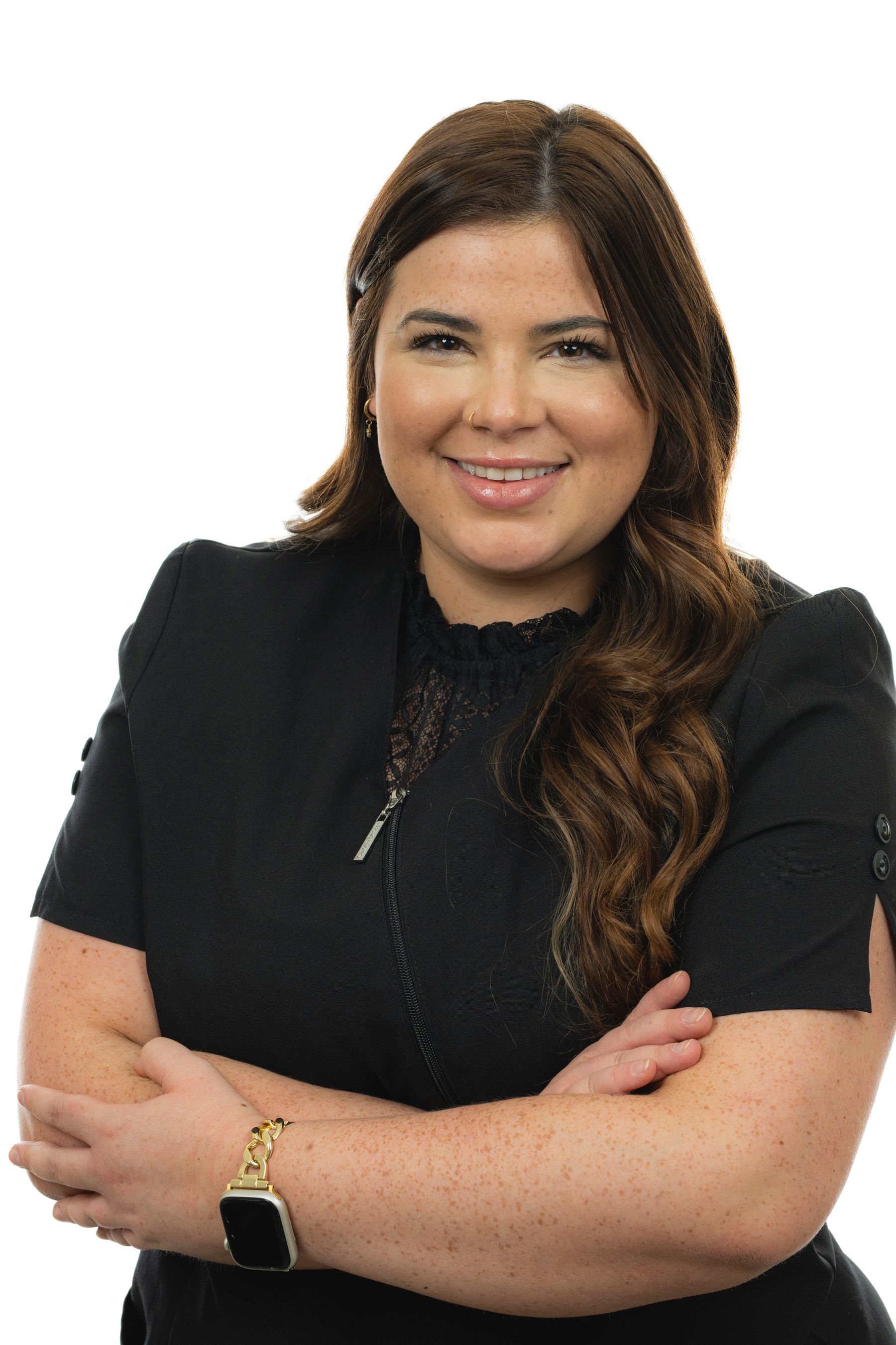 Une femme en chemise noire sourit avec les bras croisés.