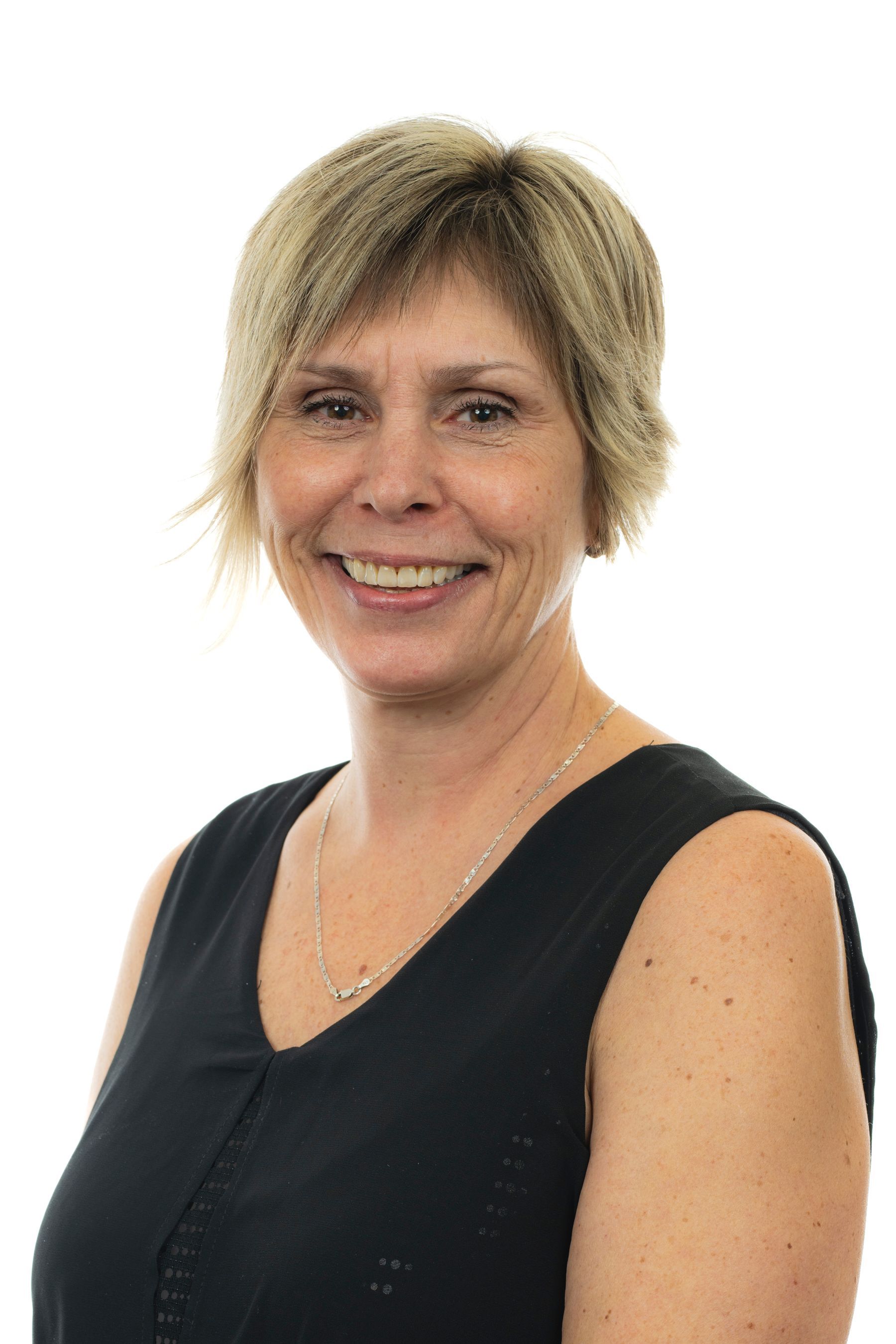 Une femme en débardeur noir sourit à la caméra.