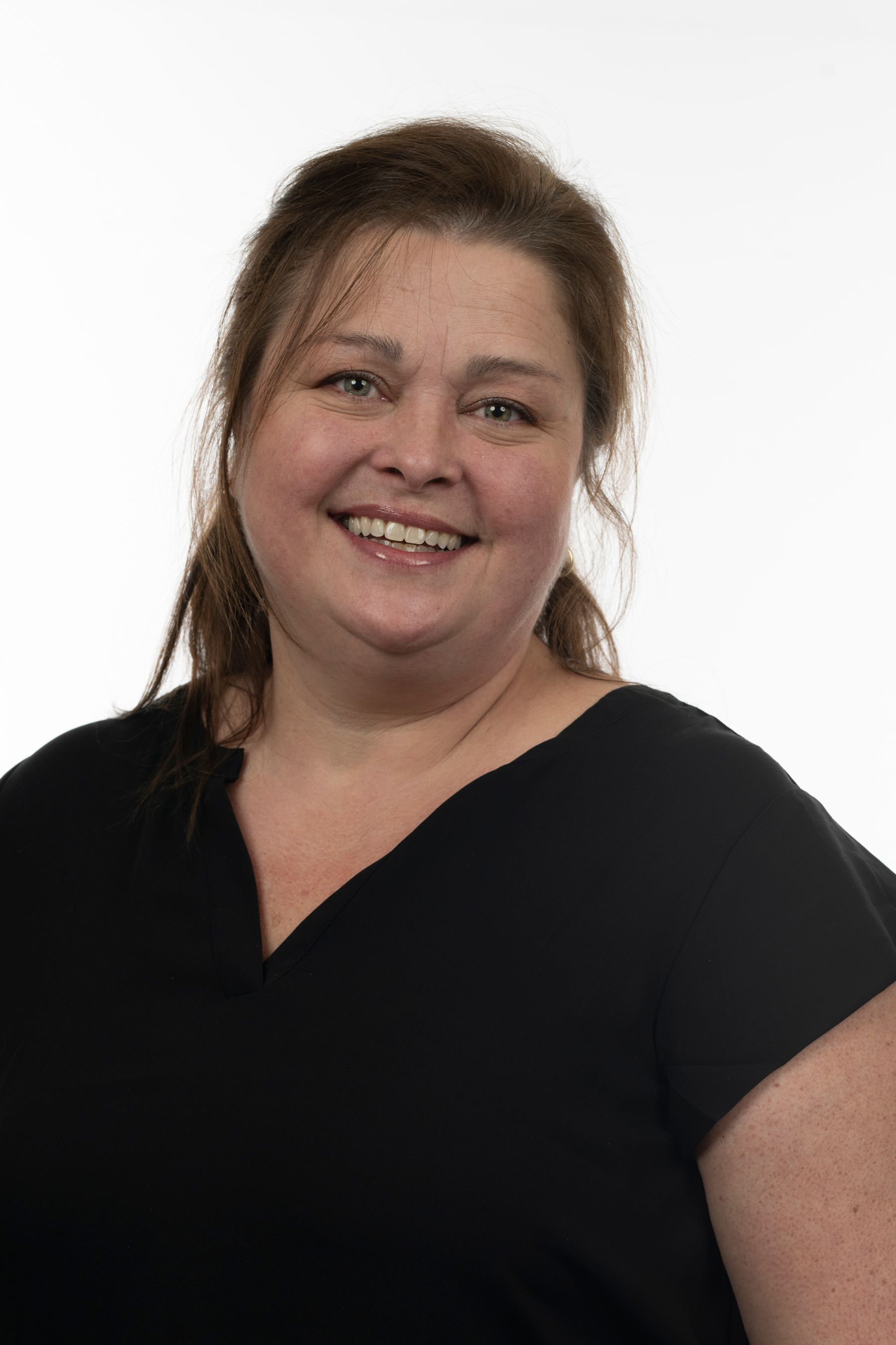 Une femme en chemise noire sourit à la caméra.
