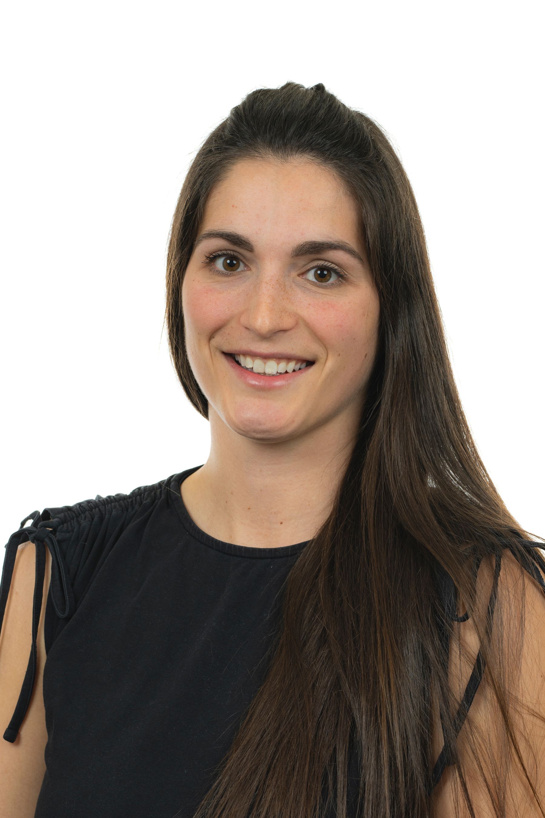 Une femme aux longs cheveux bruns sourit à la caméra