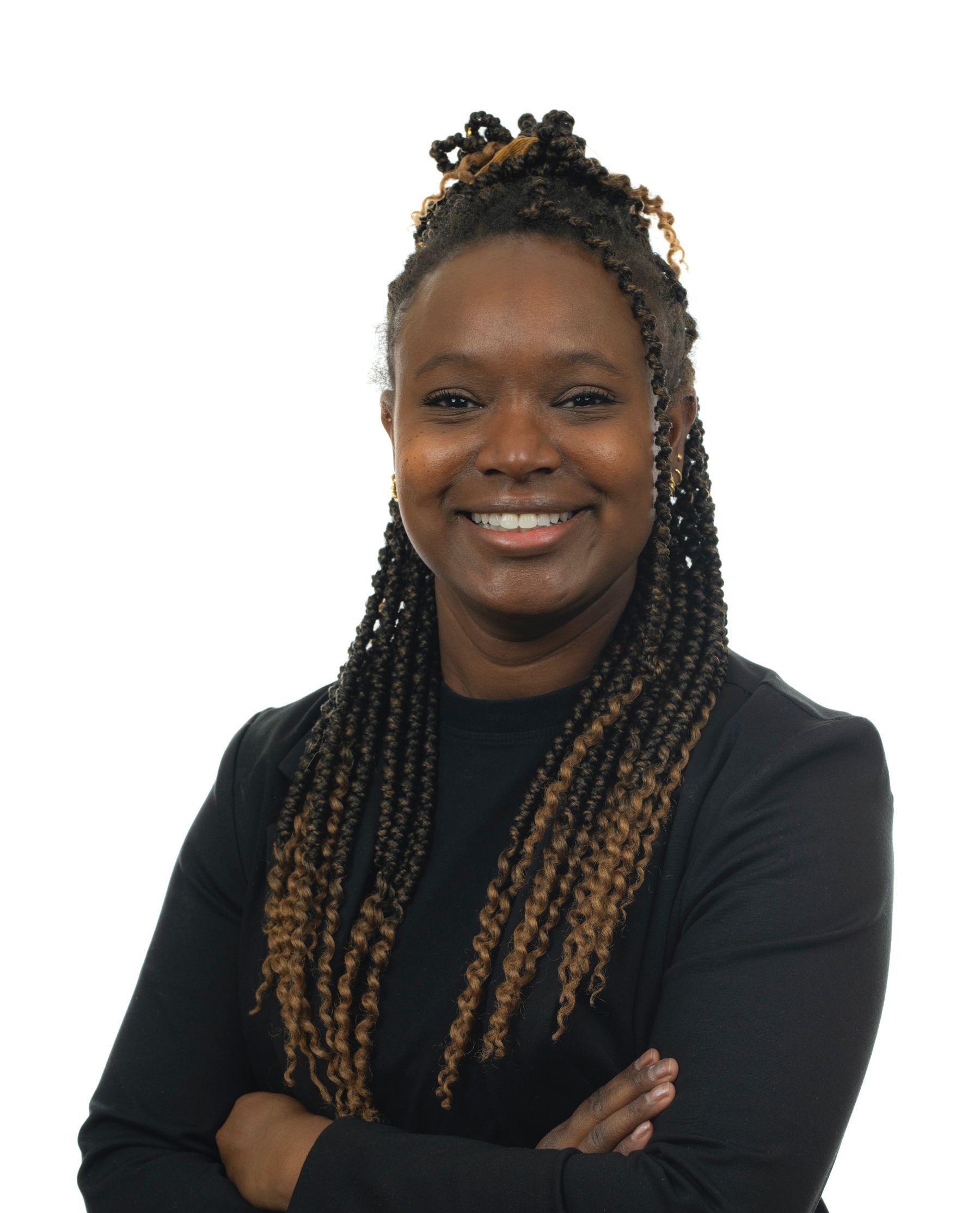 Une femme avec des tresses sourit avec les bras croisés