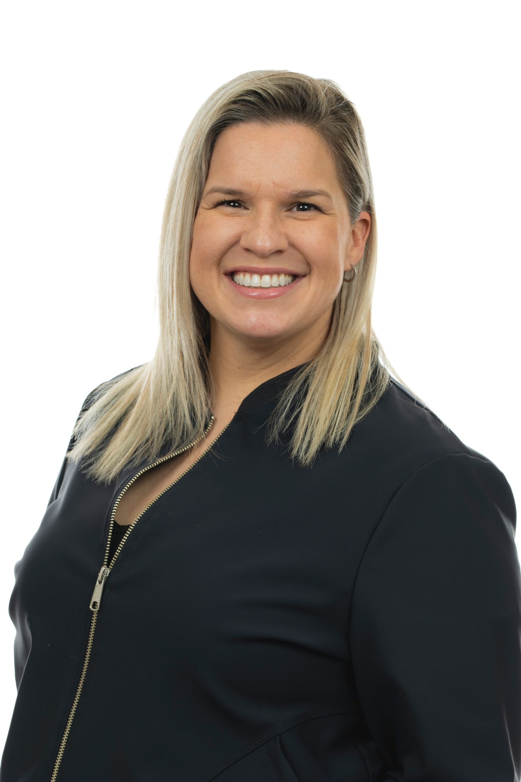 Une femme en veste noire sourit à la caméra.