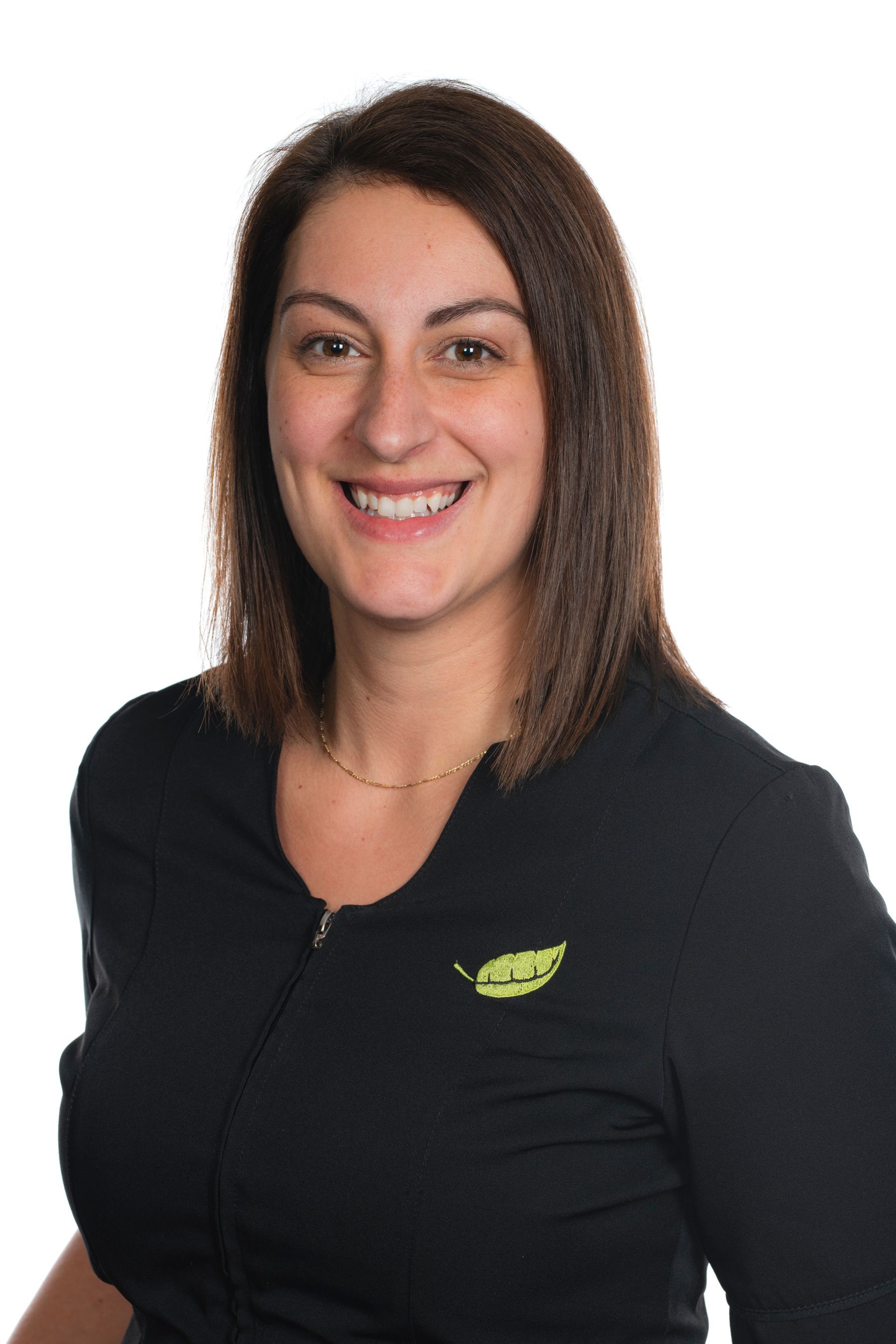 Une femme portant une chemise noire avec une feuille dessus sourit.