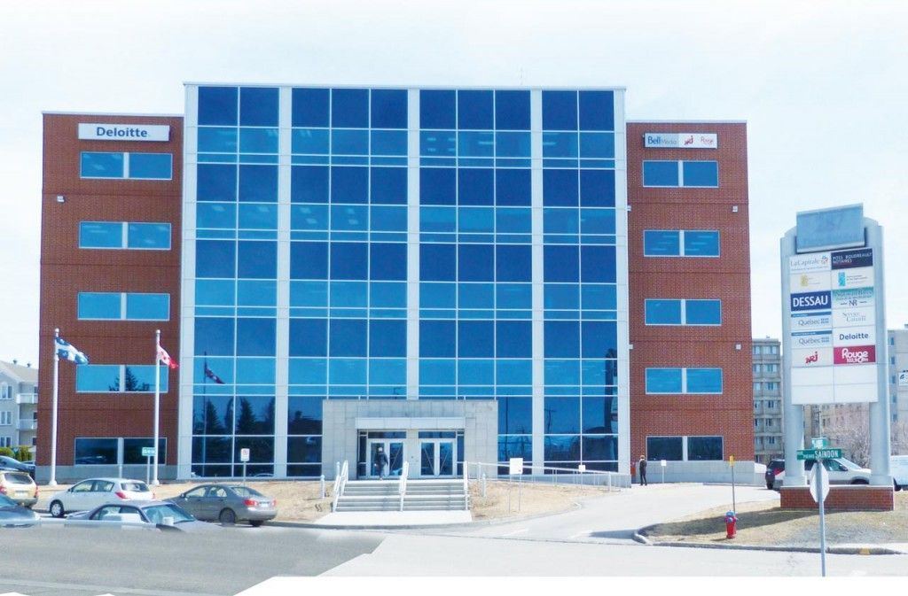 Un grand bâtiment avec beaucoup de fenêtres et des voitures garées devant