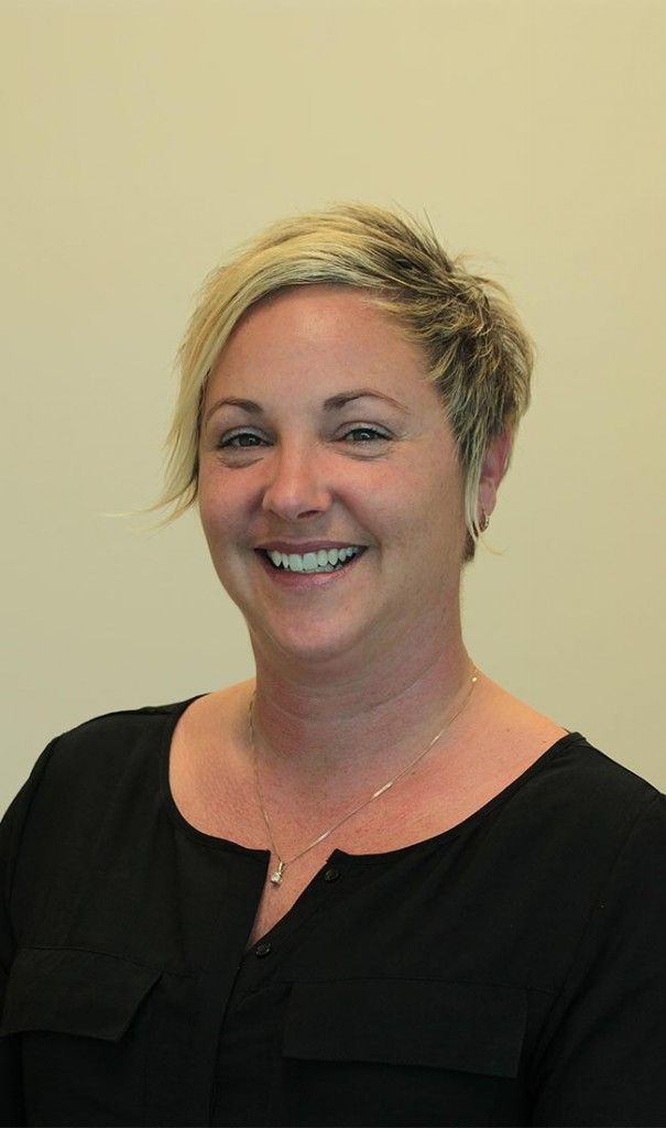 Une femme en chemise noire sourit à la caméra.