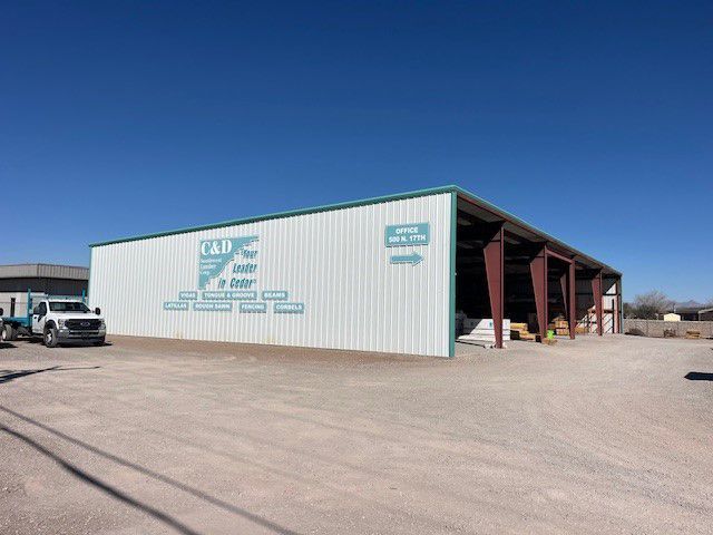 A white building with a green roof and a truck parked in front of it.