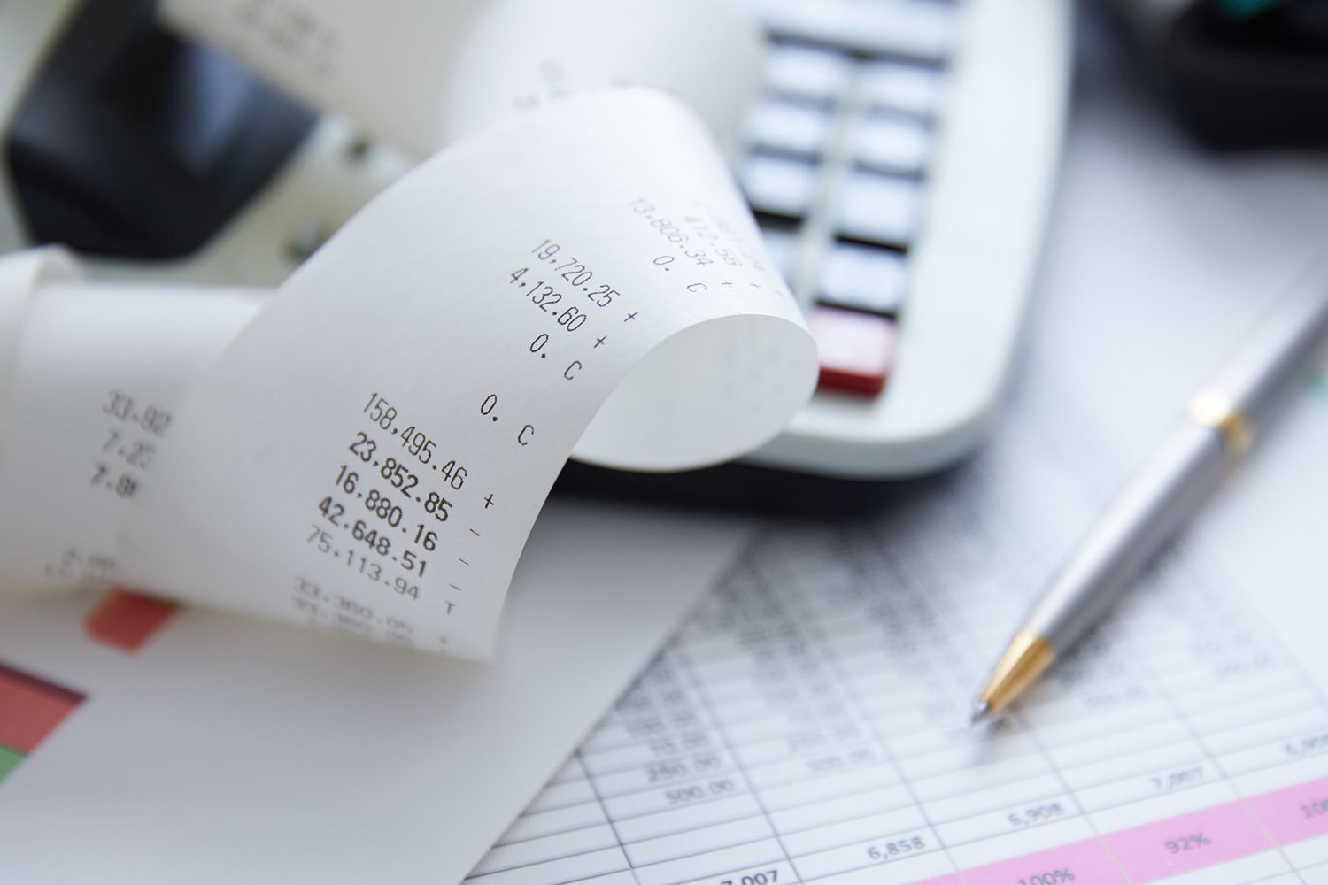 Receipt and calculator with pen and financial papers.