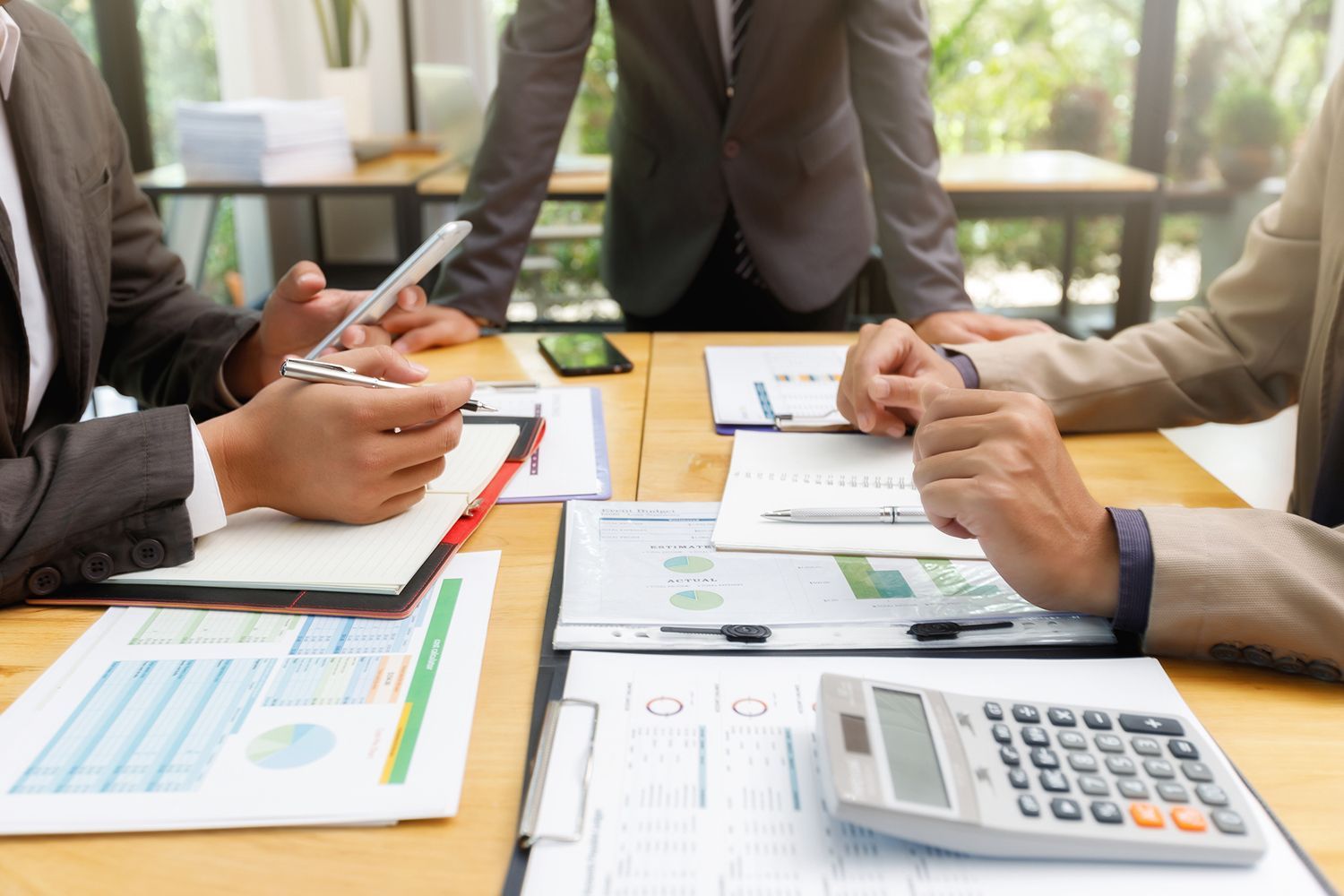 Business meeting with charts, calculator, and people in suits.