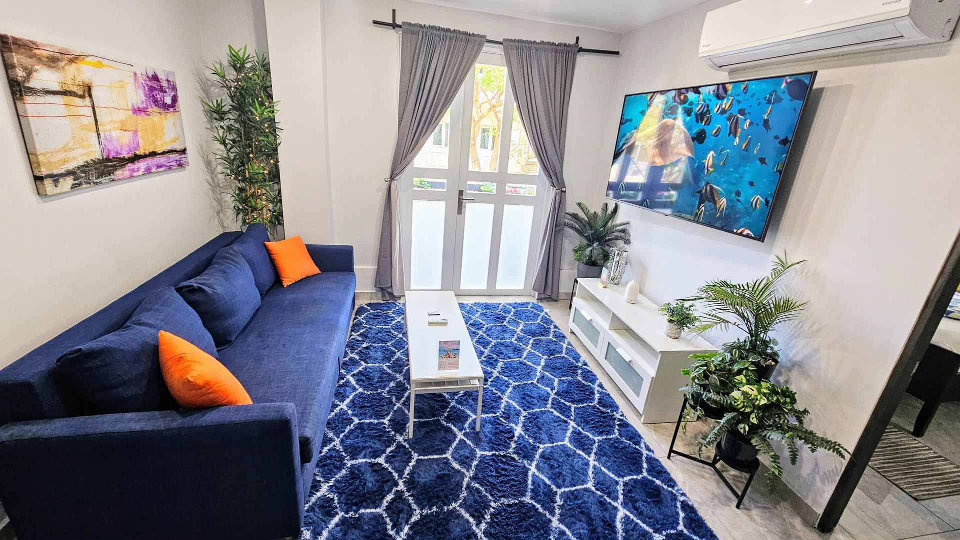 A living room with a blue couch and a blue rug.