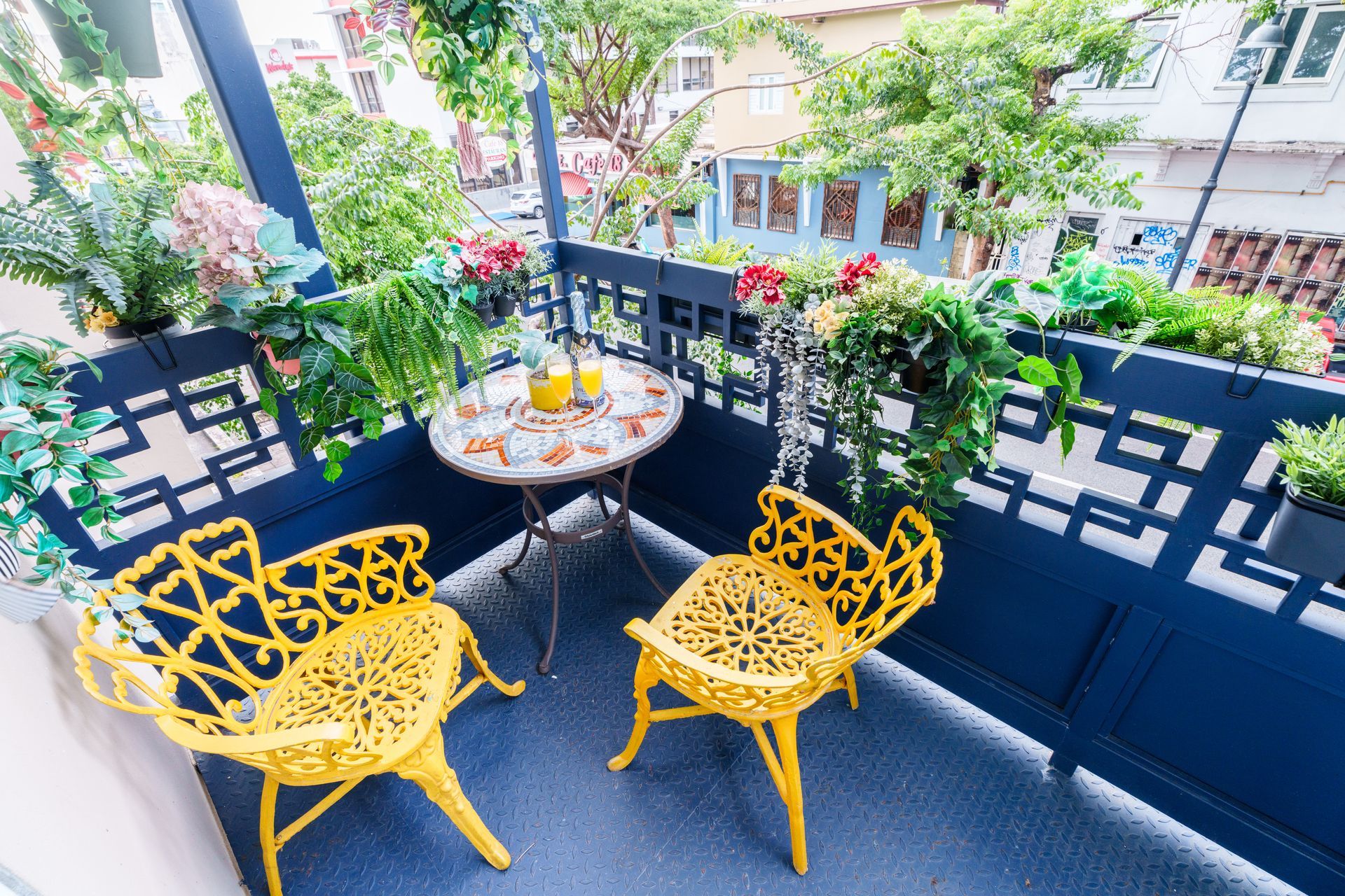 There are two yellow chairs a nd a table on the balcony. Somos Hotel San Juan, Puerto Rico Avenida Ponce de Leon