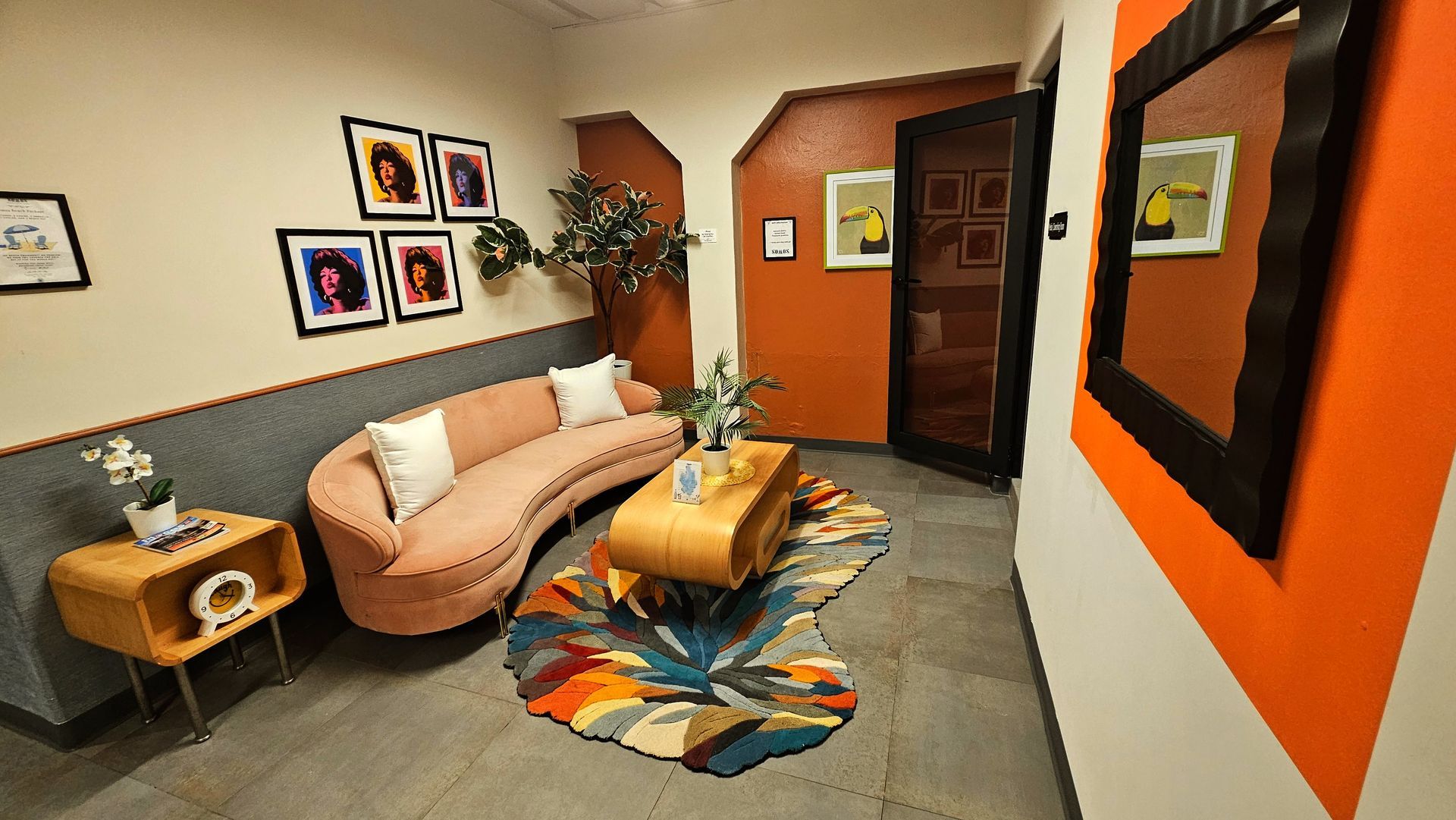 A living room with a couch , coffee table , and paintings on the wall.