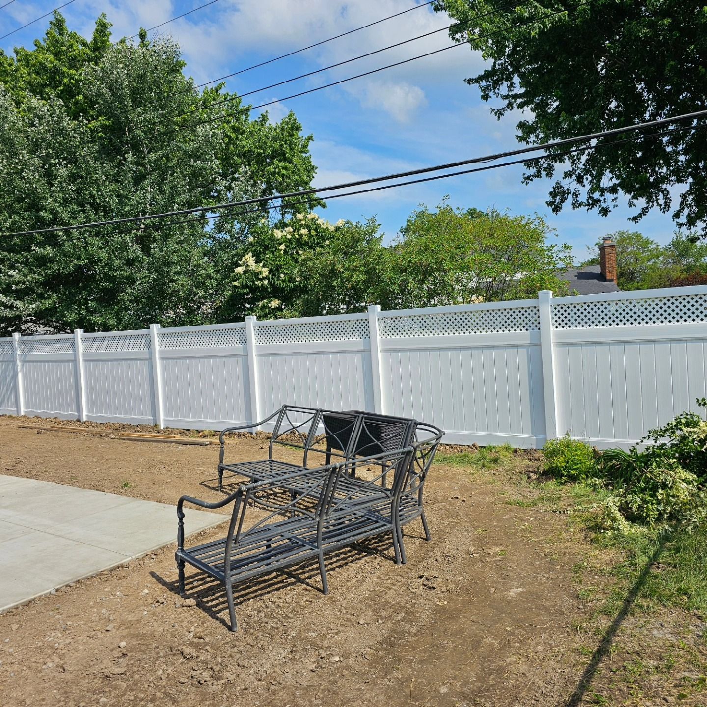 Wooden privacy fence with black posts along a grassy yard under an overcast sky